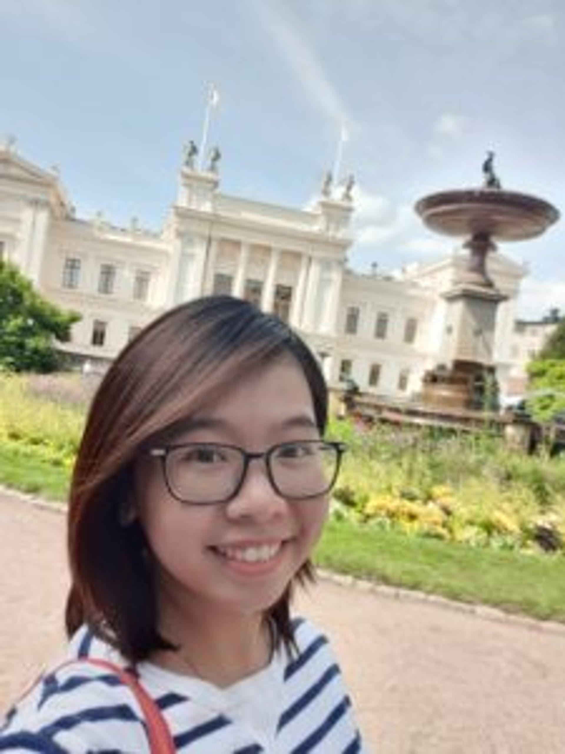 Student poses for a selfie in front of a university building.