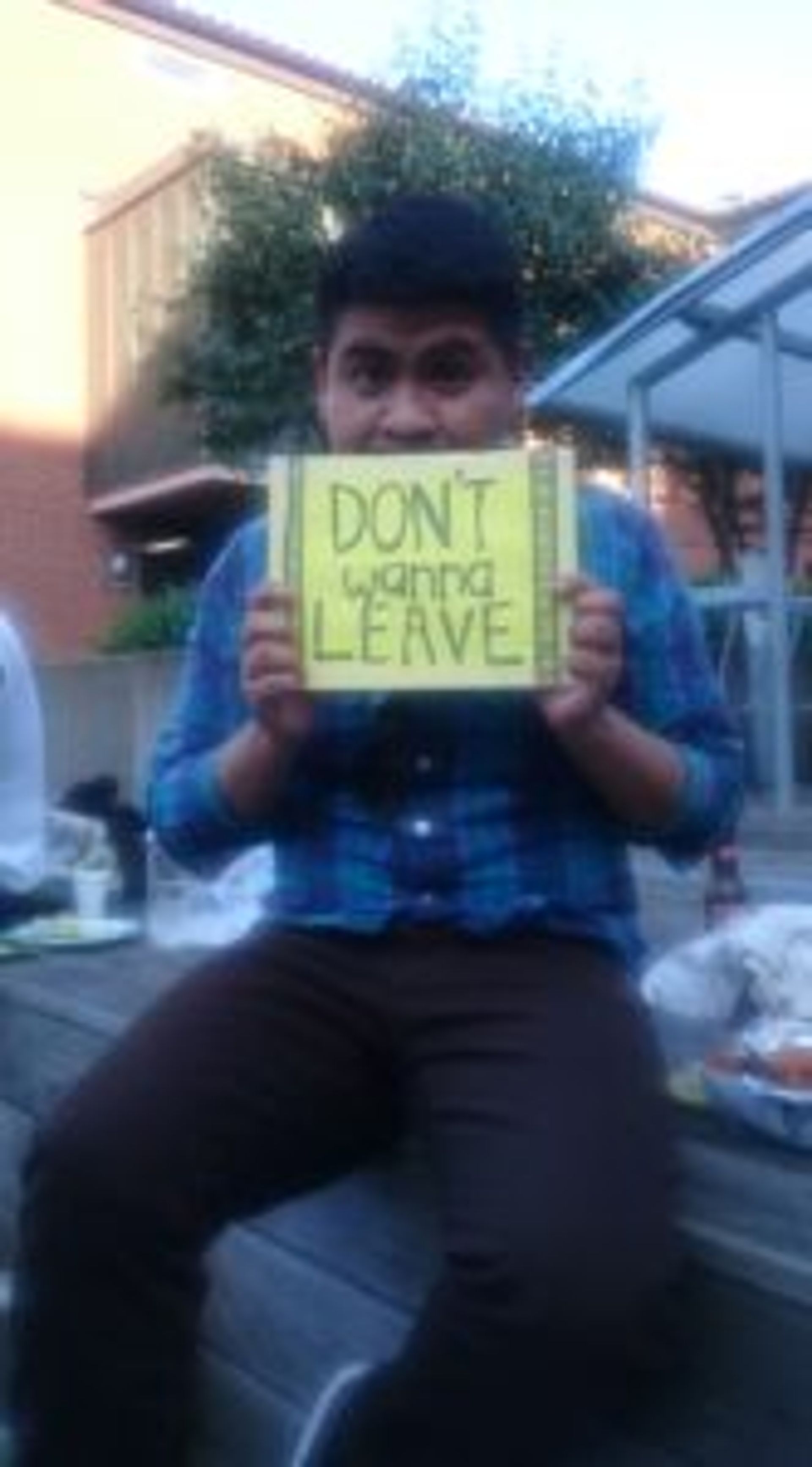Person holding a sign that reads 'Don't wanna leave'.