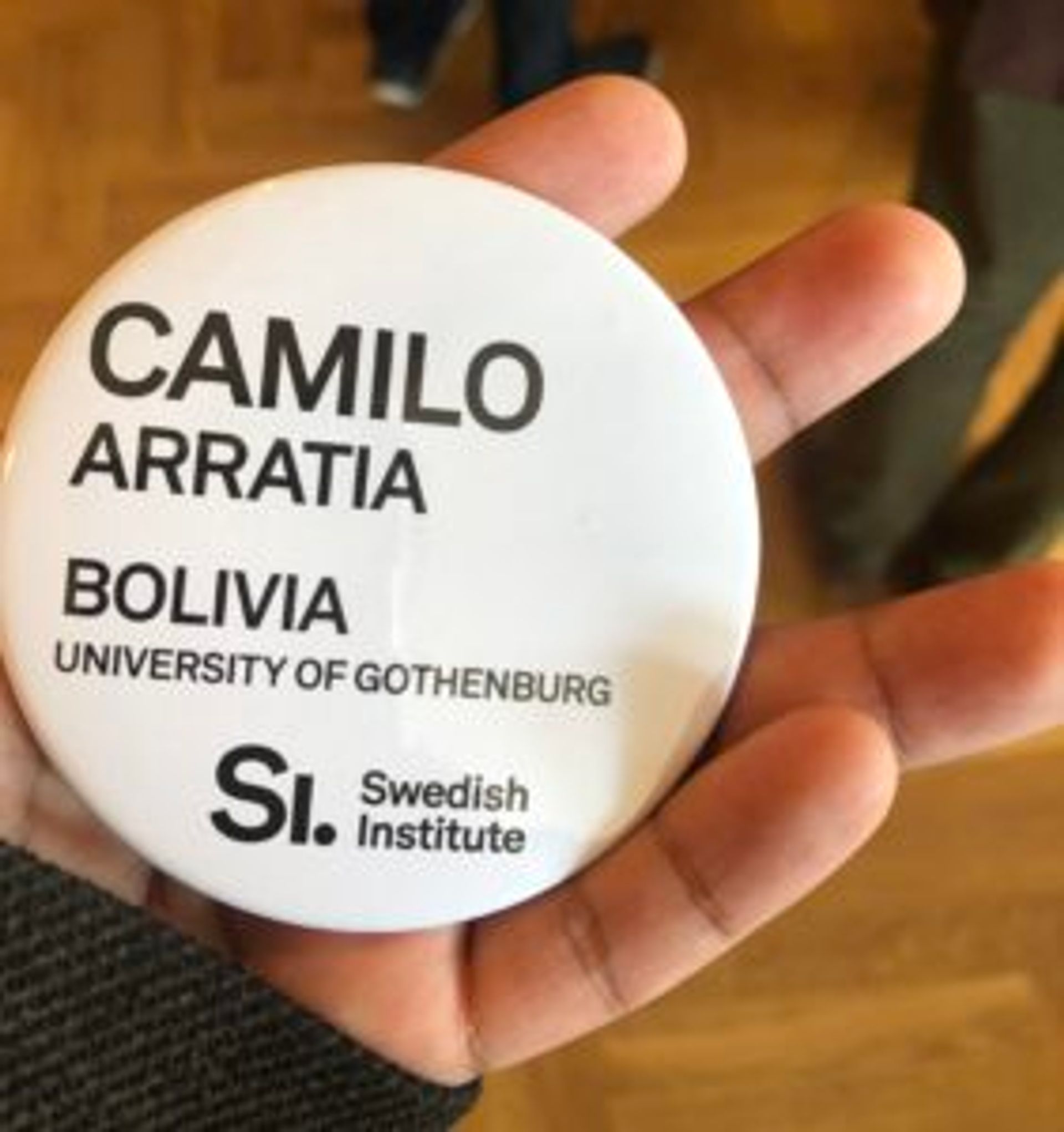 A white, round badge with the text 'Camilo Arratia. Bolivia. University of Gothenburg.' on it.