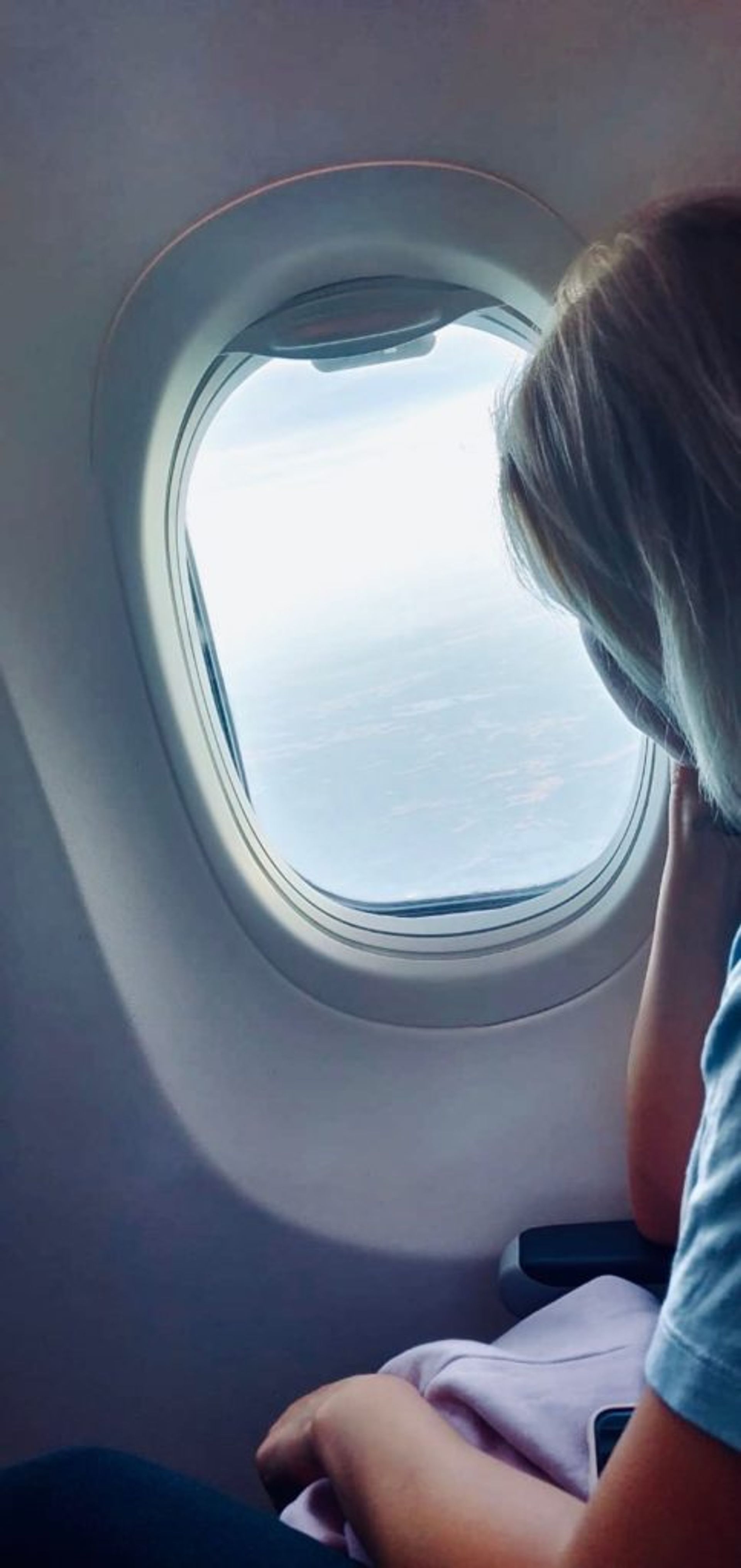 Student looking out of a plane window at the land below.