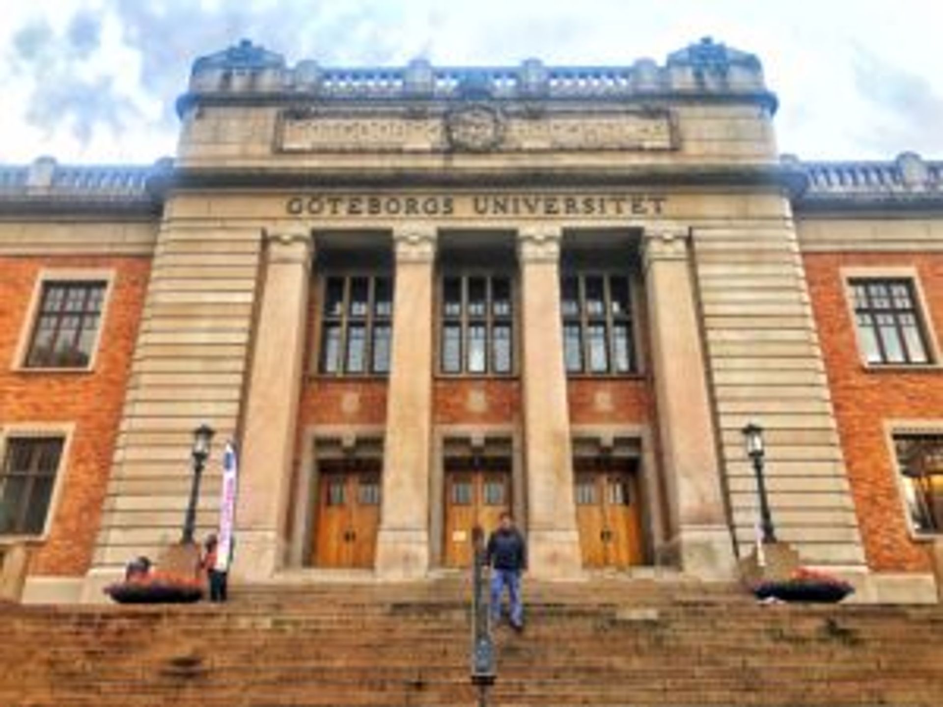 A student stands in front of a university building.