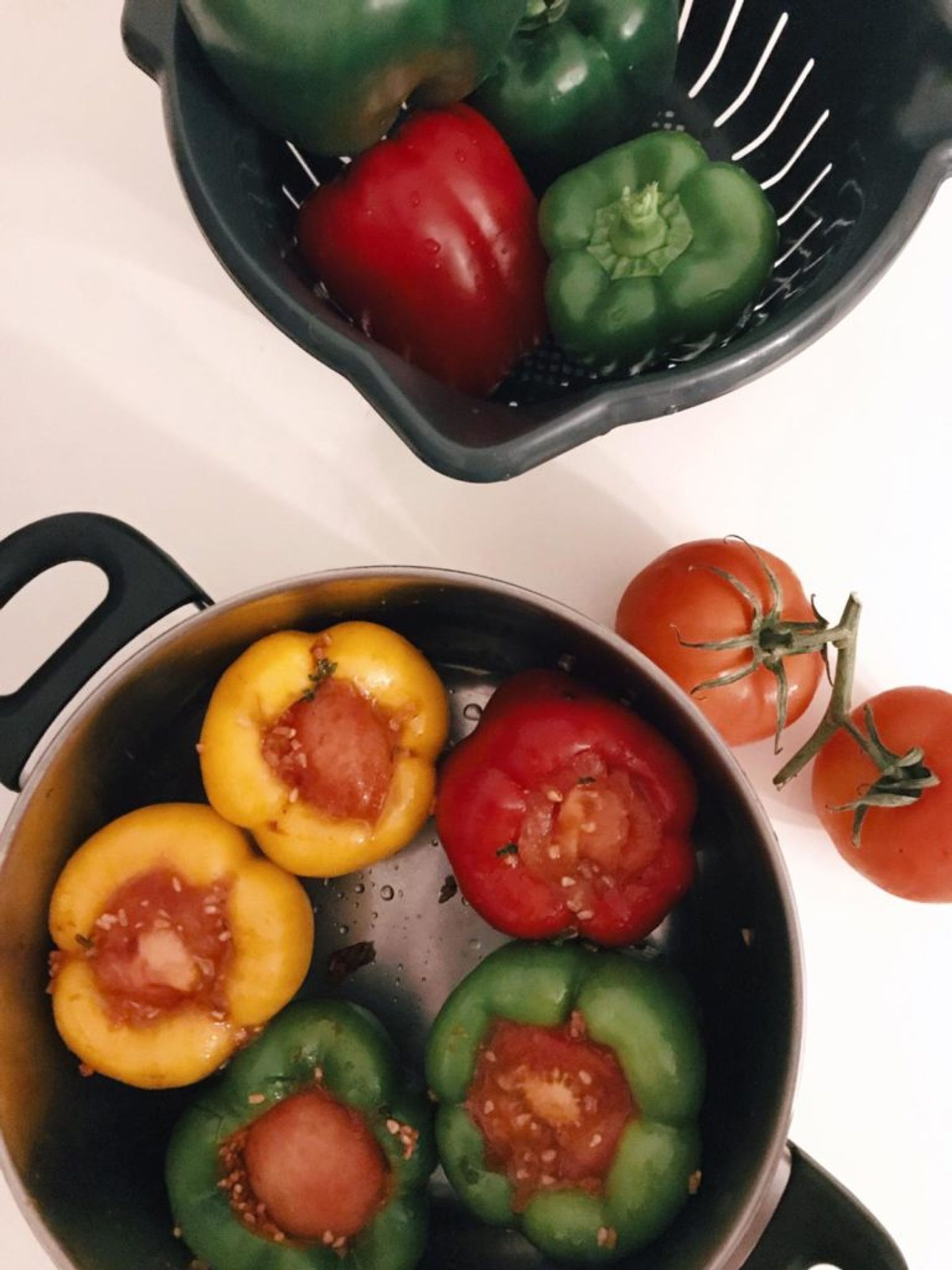 Close-up of peppers and tomatoes cooking in a pan.