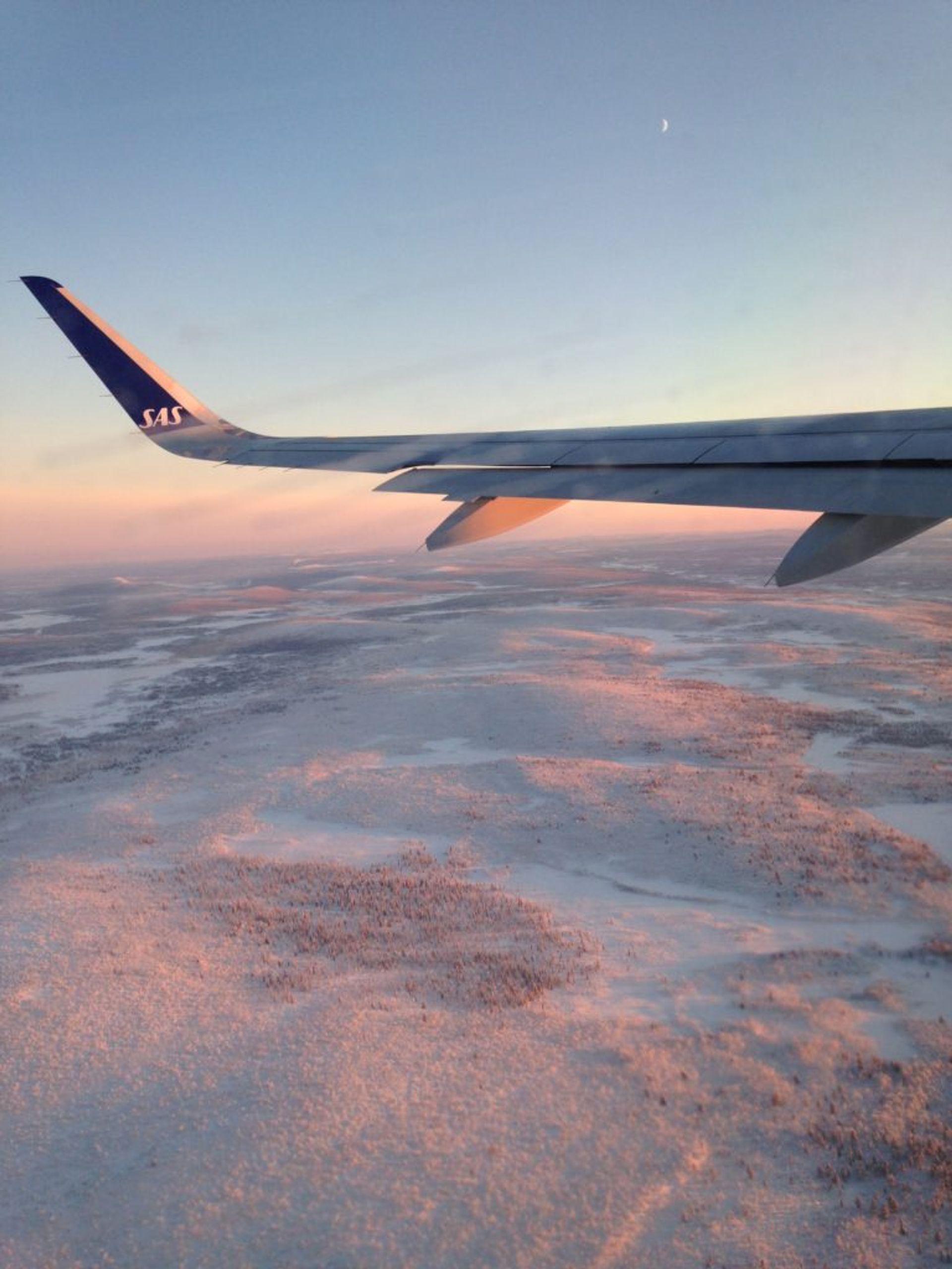 Pink and snowy landscape view from airplane 