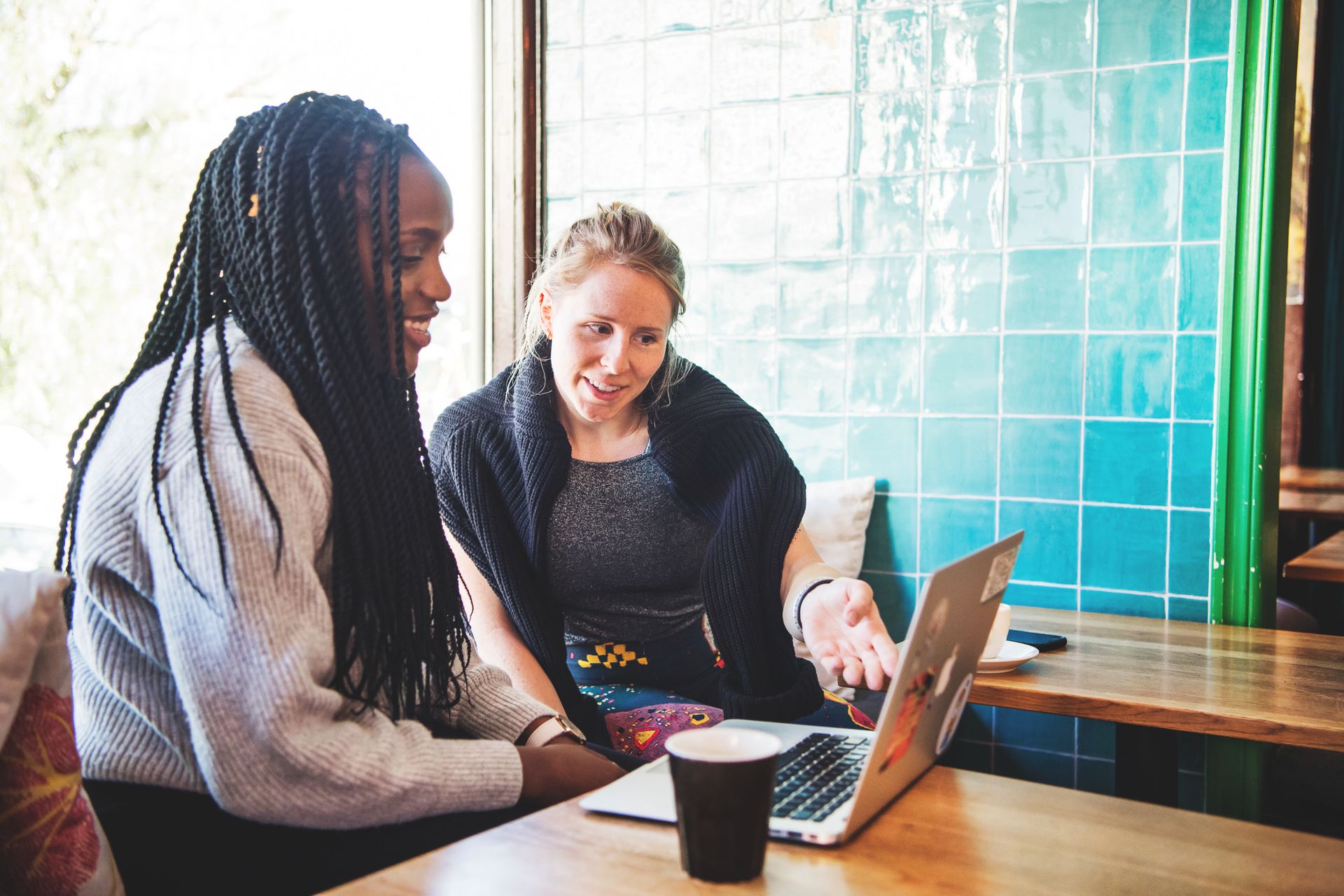 Two students using a laptop in a cafe.