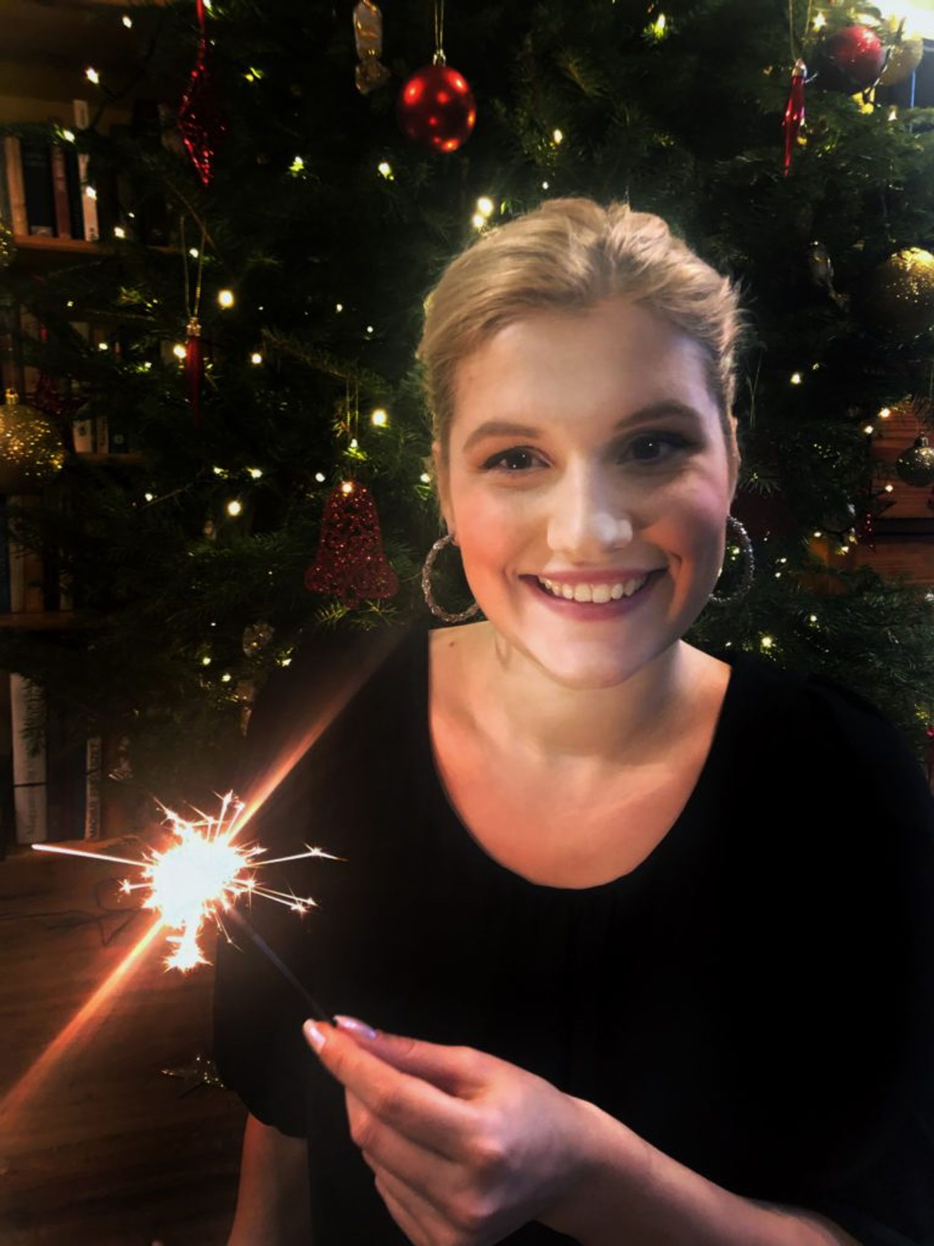 Sara in front of a Christmas tree.