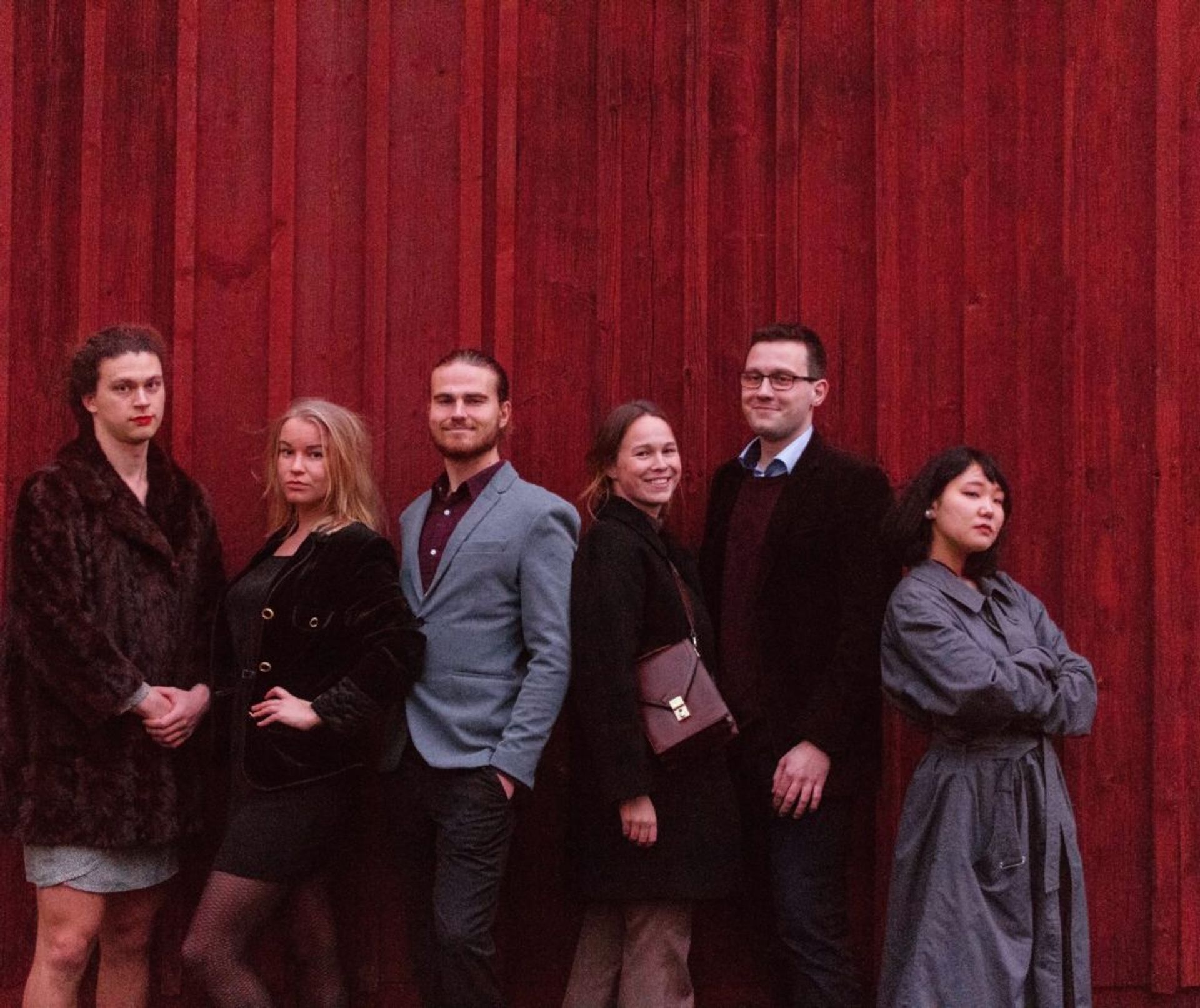 A group of people standing in front of a wooden building.