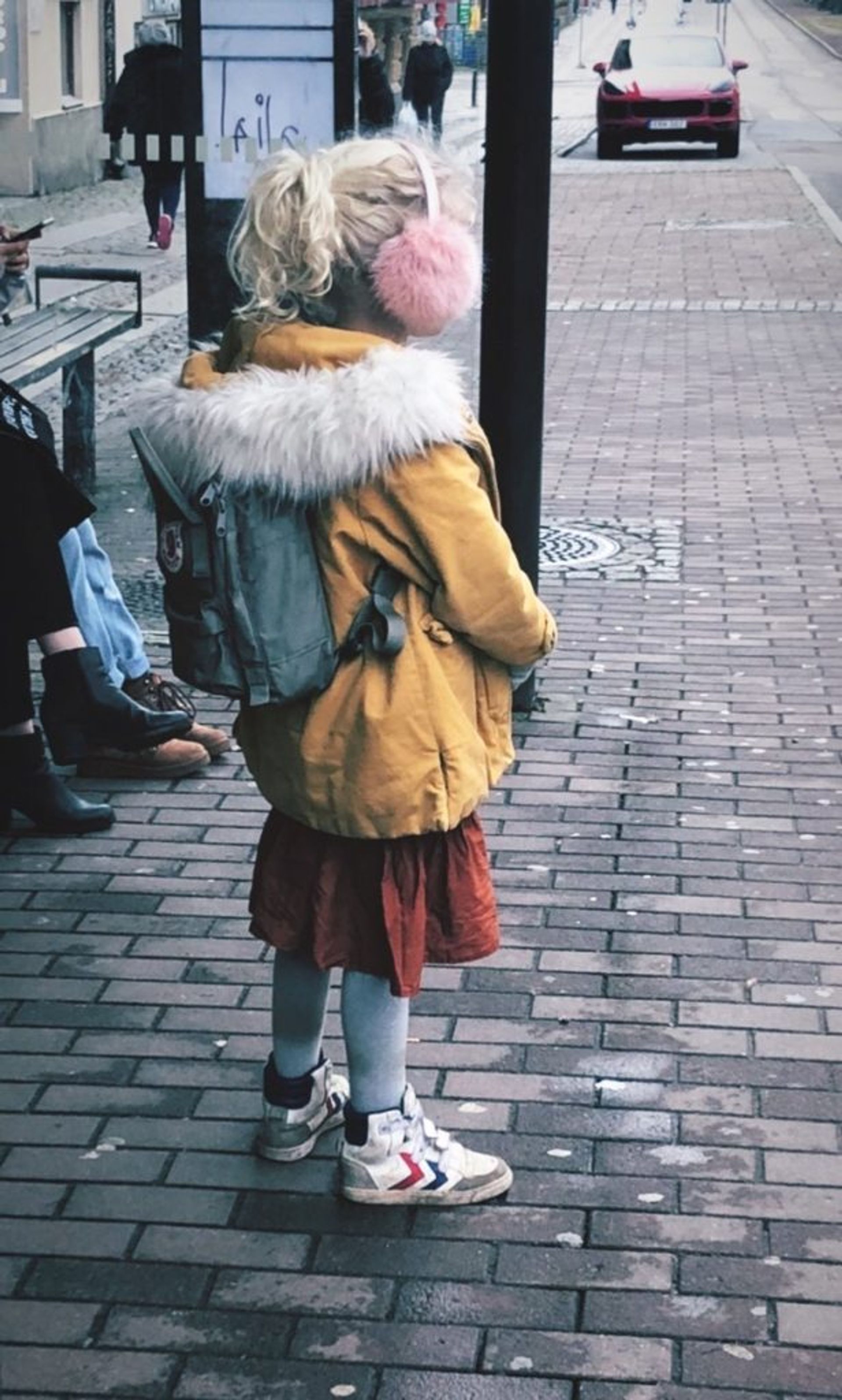 A child standing at a bus stop.