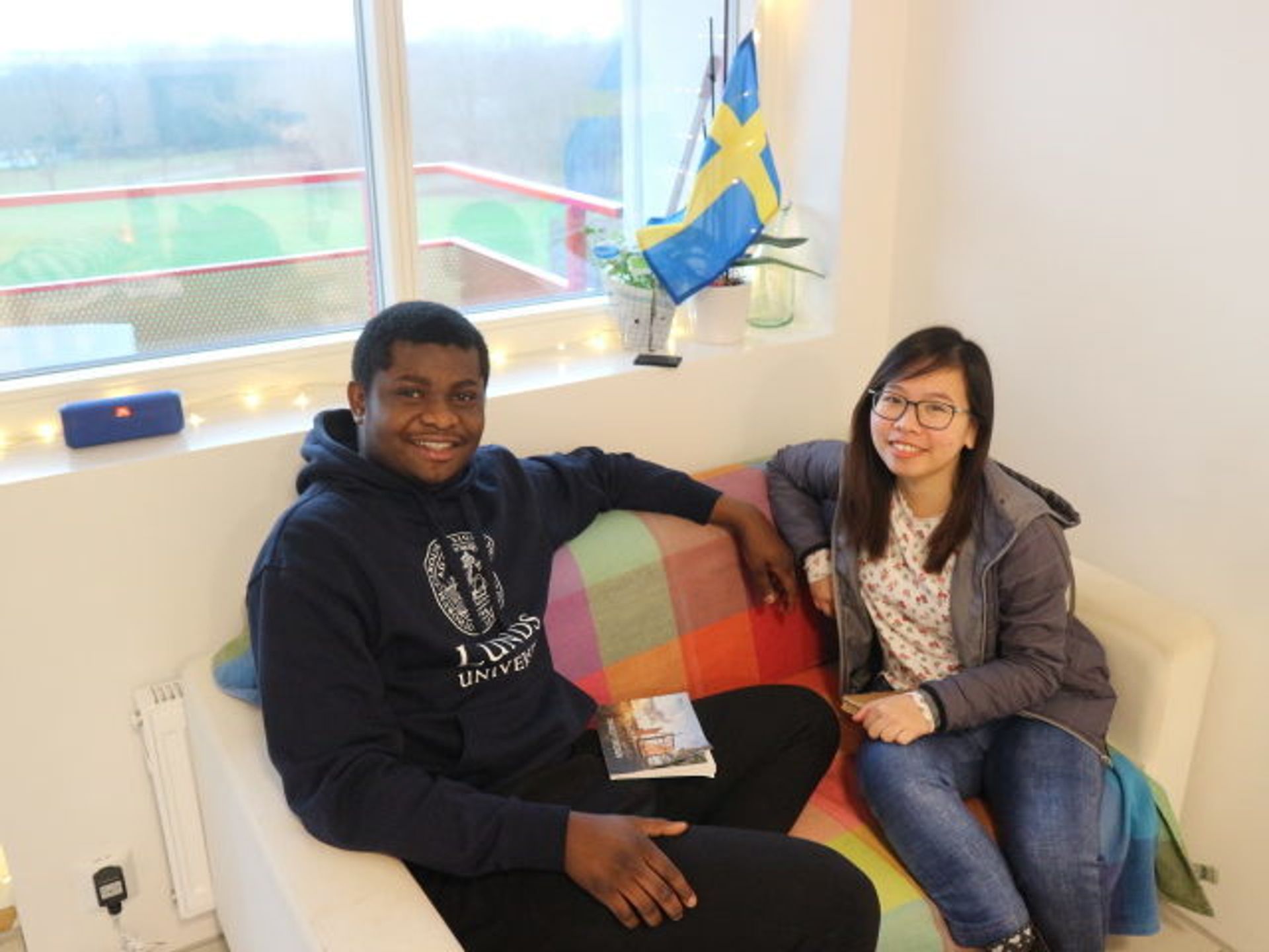 Two students sit on a sofa together.