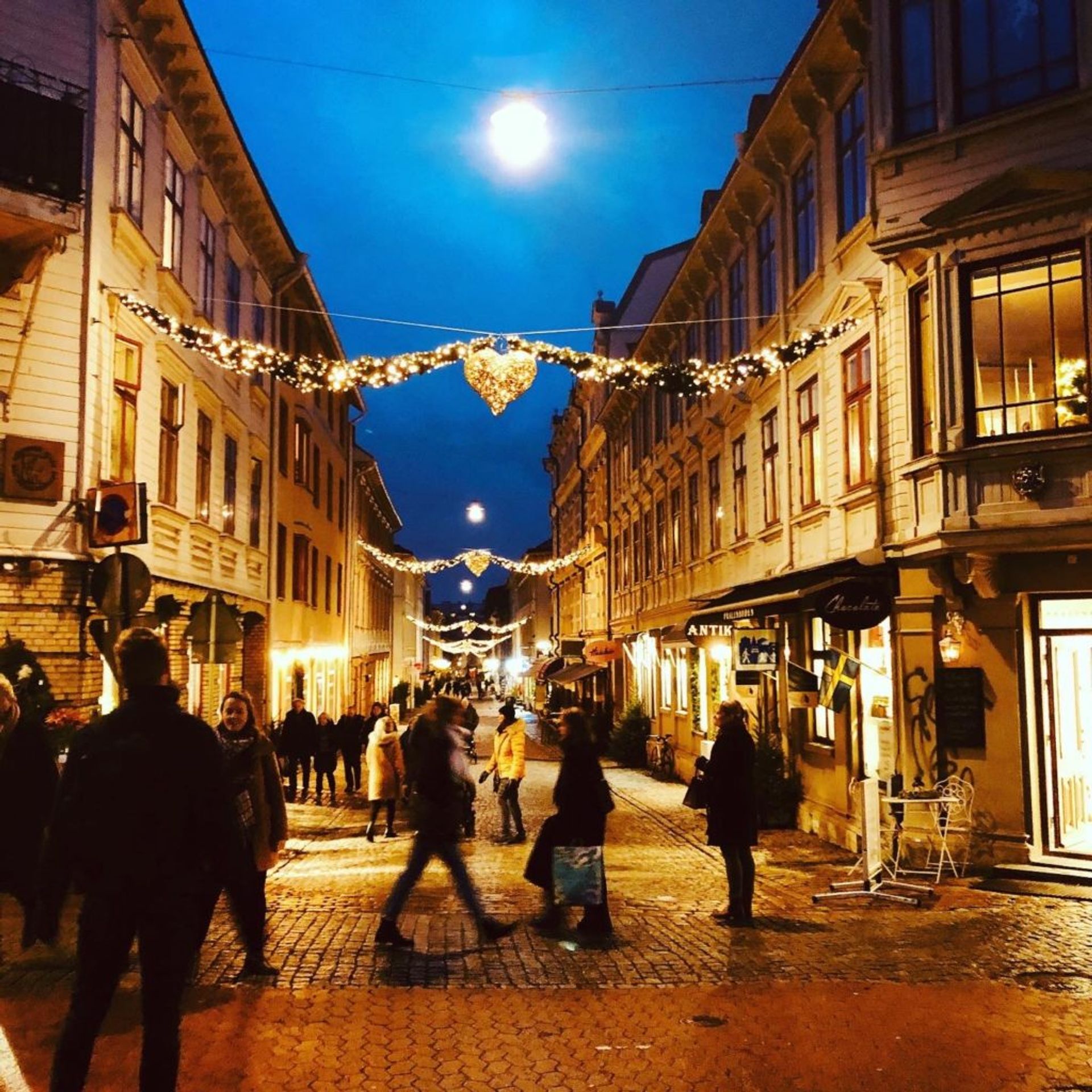 A busy street at night, lit up by Christmas lights.