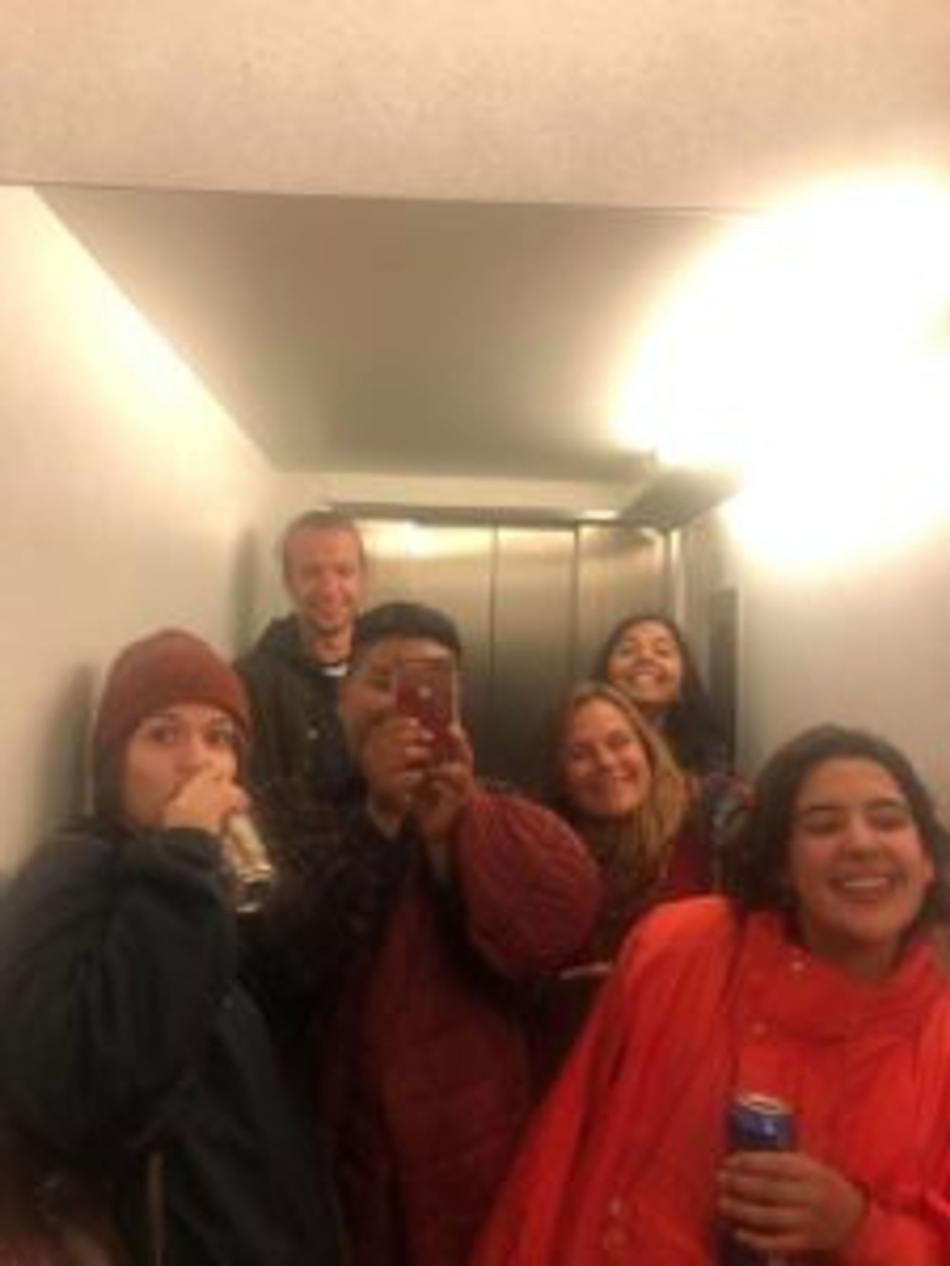 Camilo taking a selfie in an elevator's mirror surrounded by five friends.