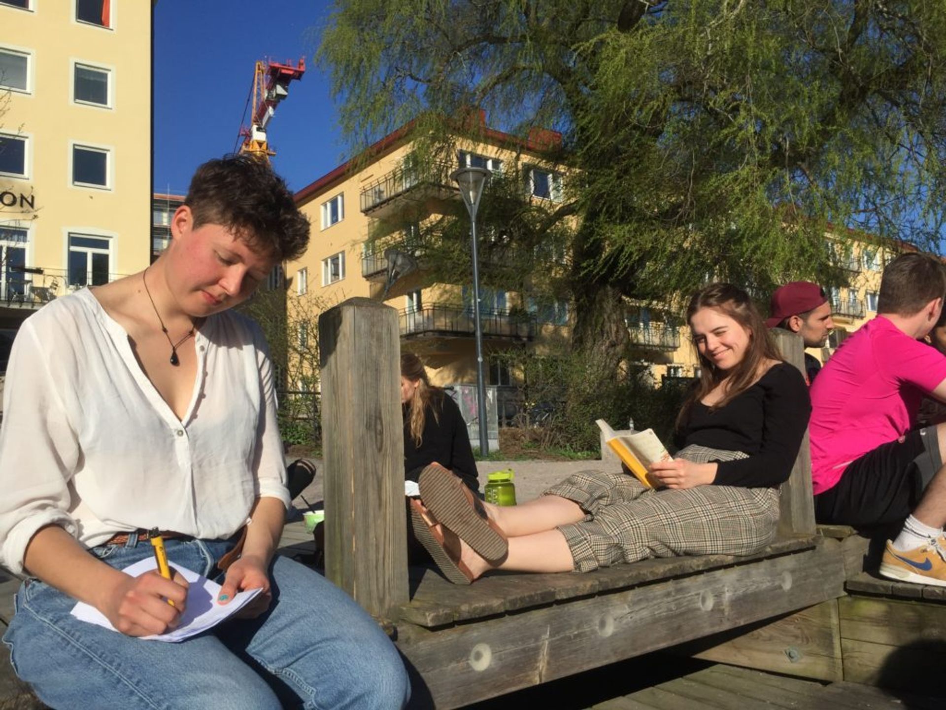 Two students sitting on wooden steps by the river reading and taking notes.