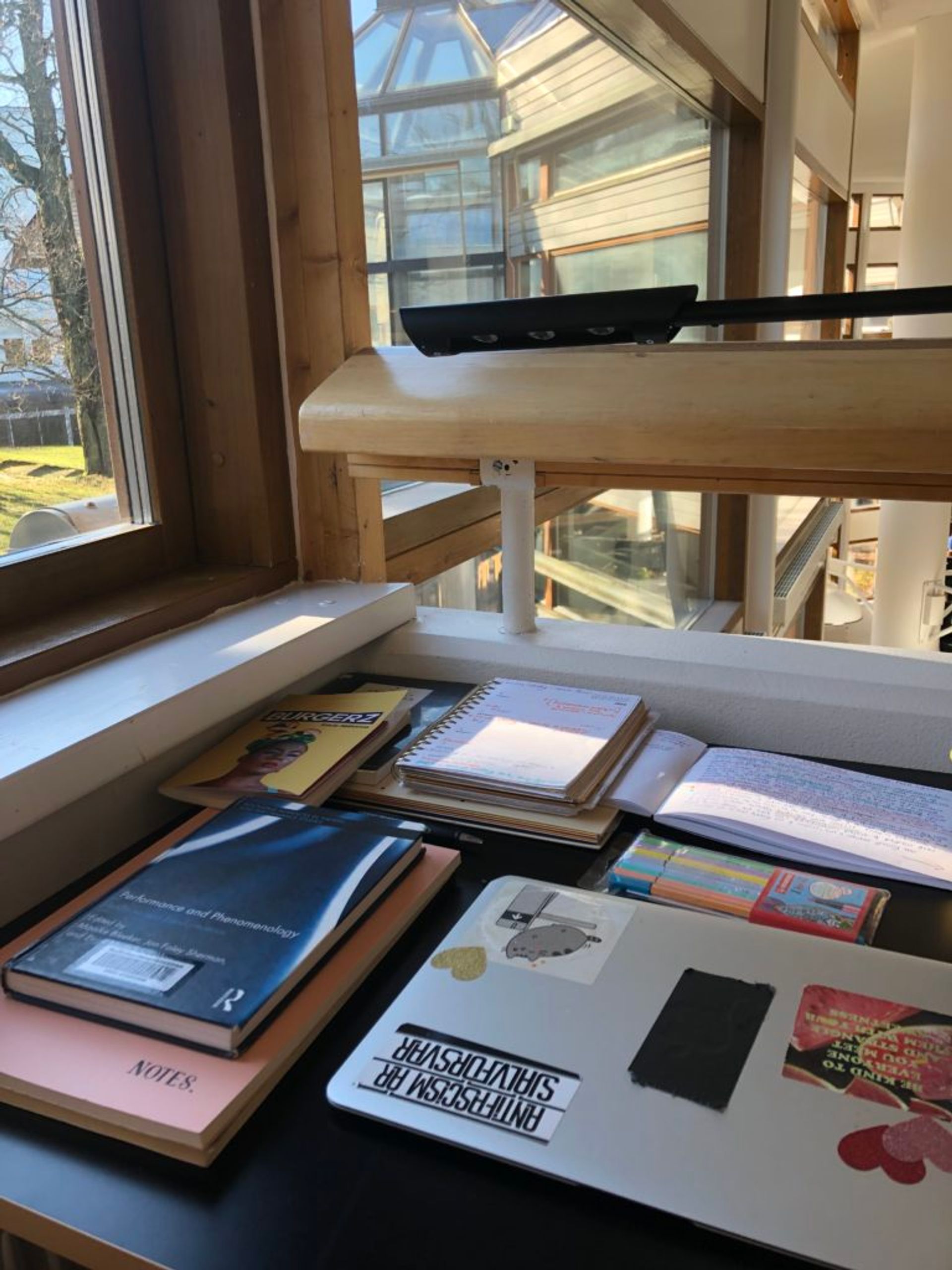 Several library books, notebooks and a laptop on a desk in the Stockholm University library.