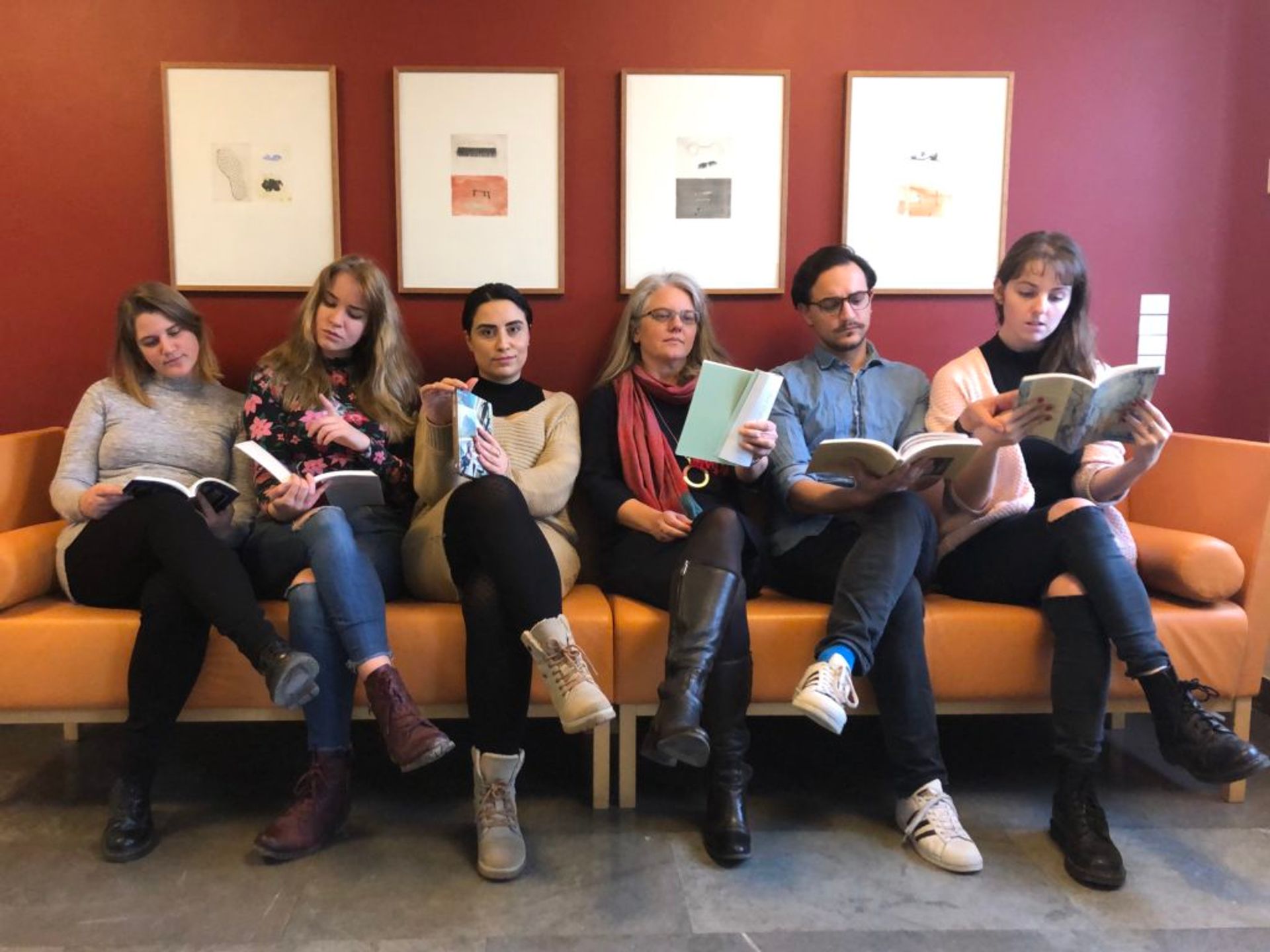 Emma sits with her teacher and coursemates on a sofa, reading books, clearly posing for the photo.