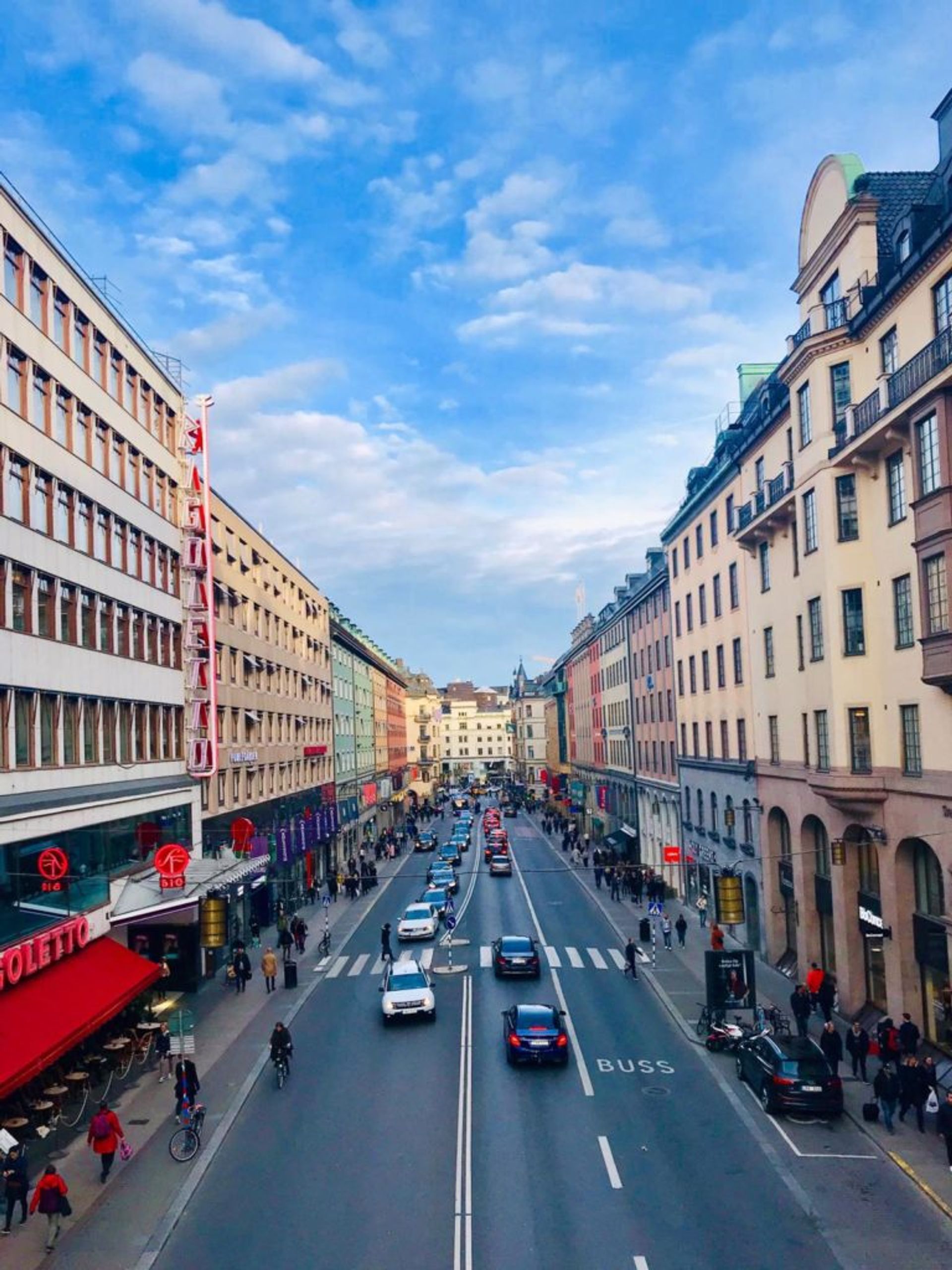 A street in central Stockholm. Lots of people are walking up and down the pavements.