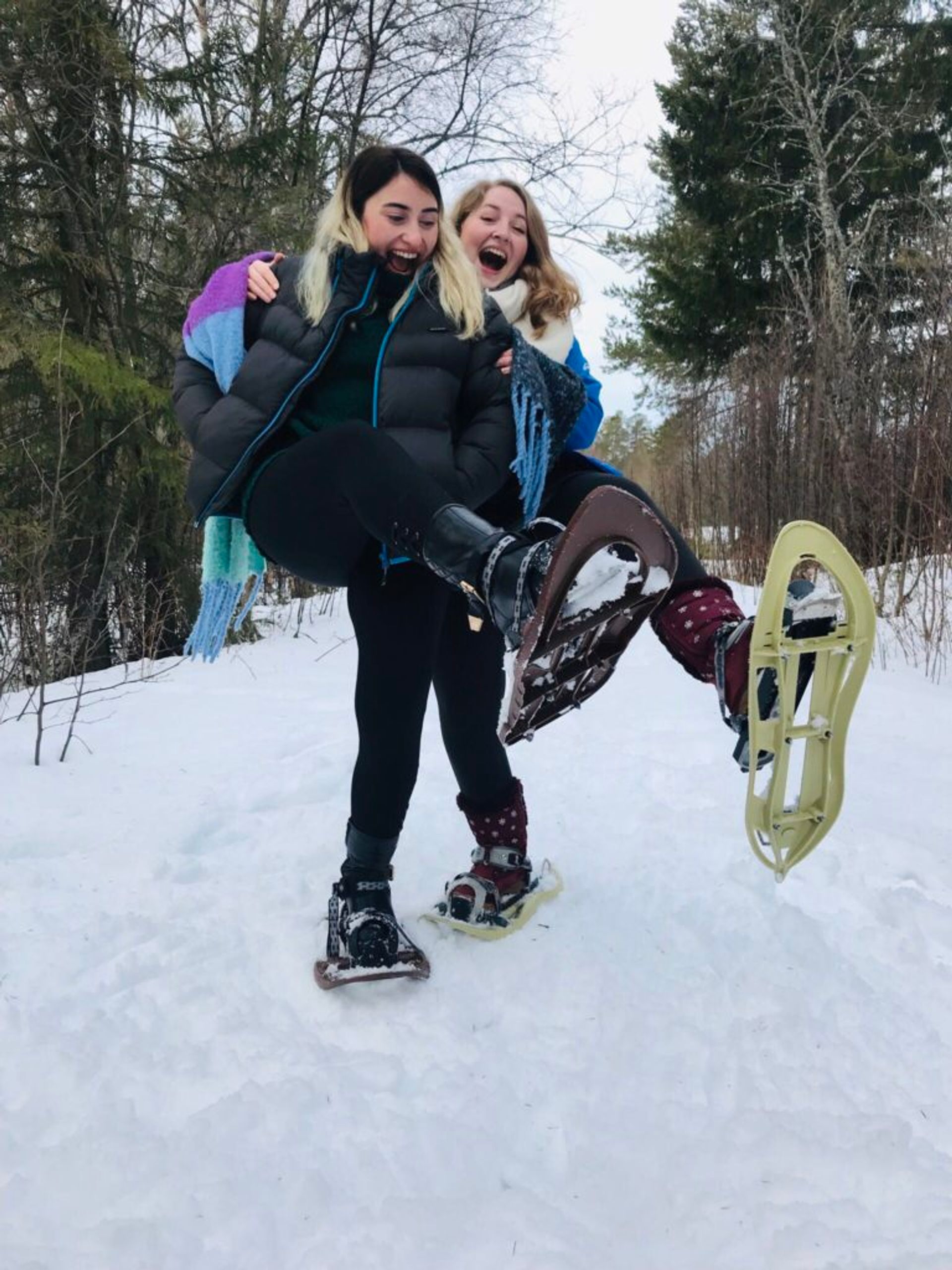 Hazal and Katharina standing in the snow wearing snowshoes.