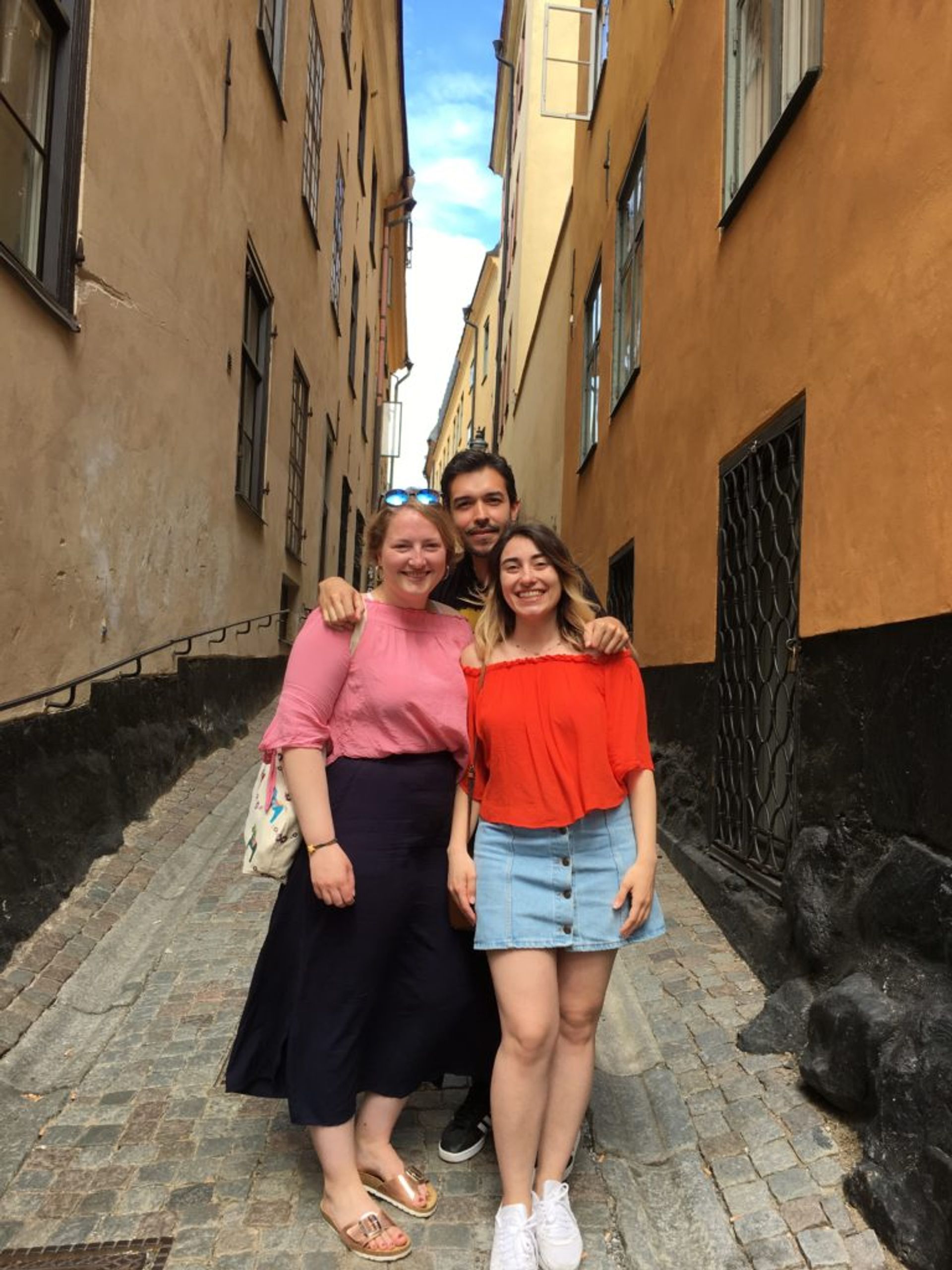 Hazal and two friends, Katharina and Daniel, standing close together on a cobbled street in Stockholm's Old Town.