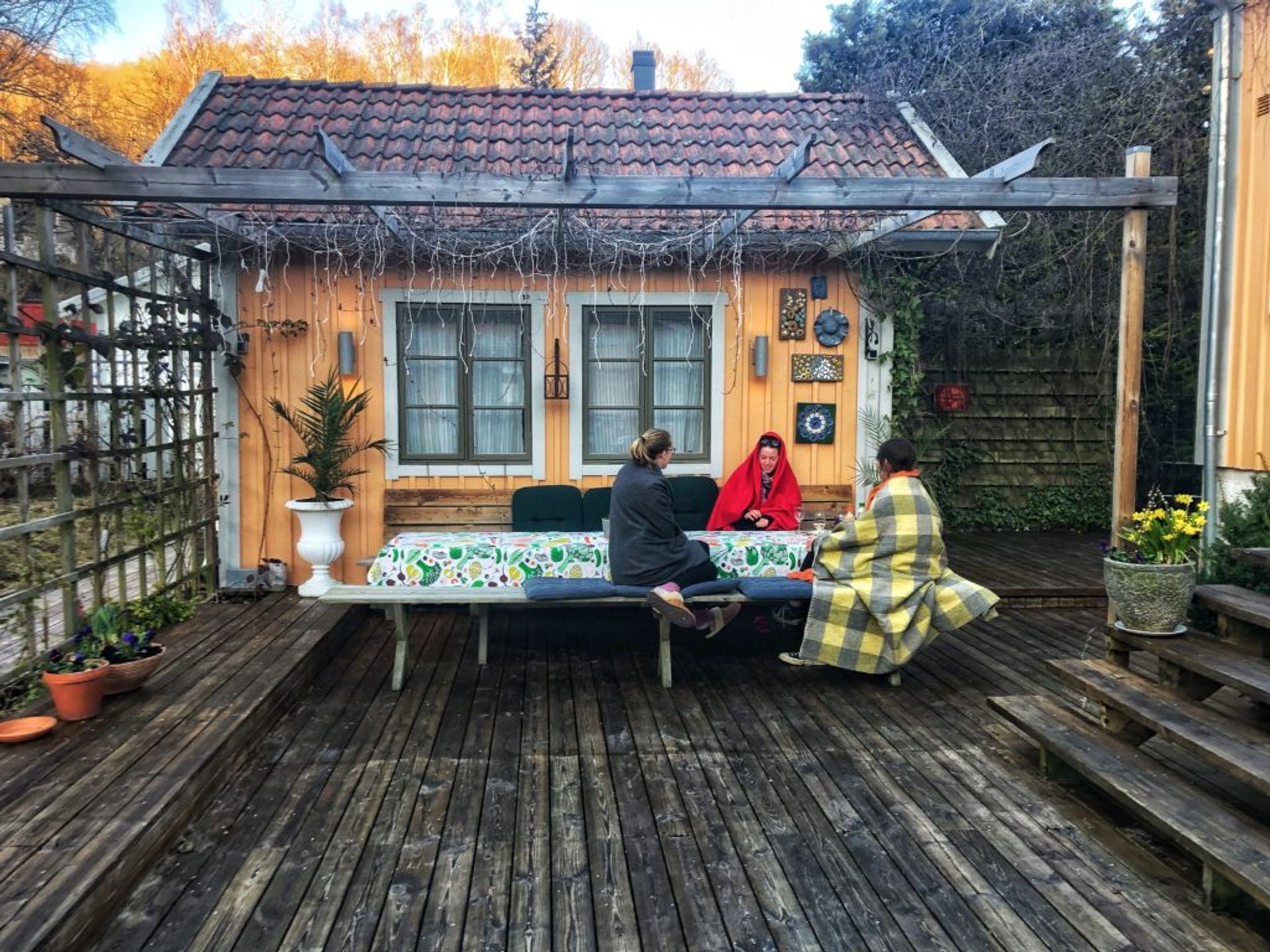 Sara and two flatmates sitting at a table on the patio by their apartment building.