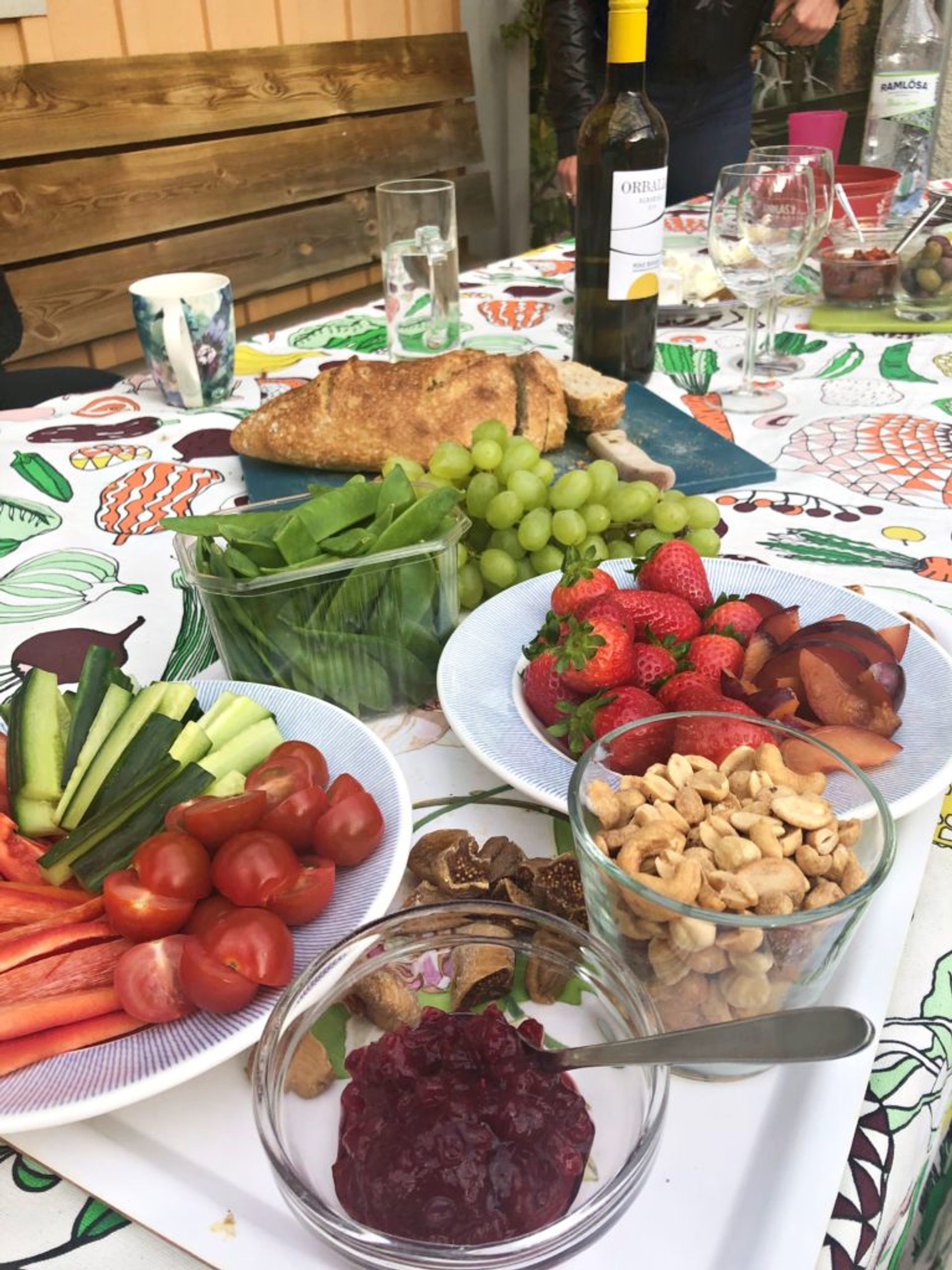 A table outside covered in plates of fresh fruit and vegetables.