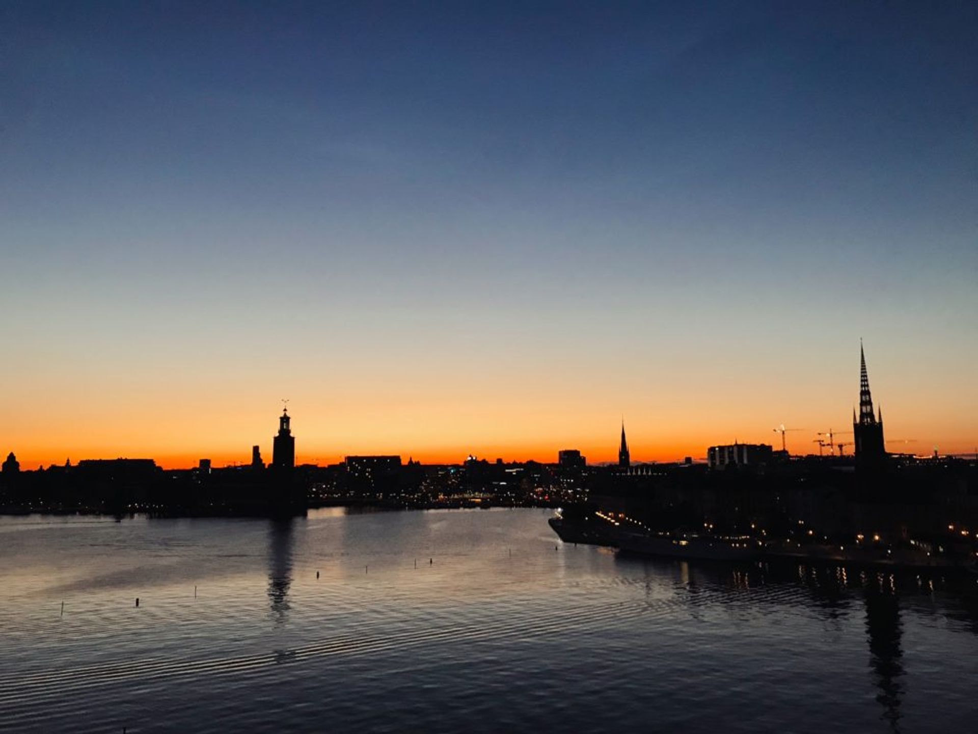 The Stockholm skyline silhouetted against a bright orange sunset.