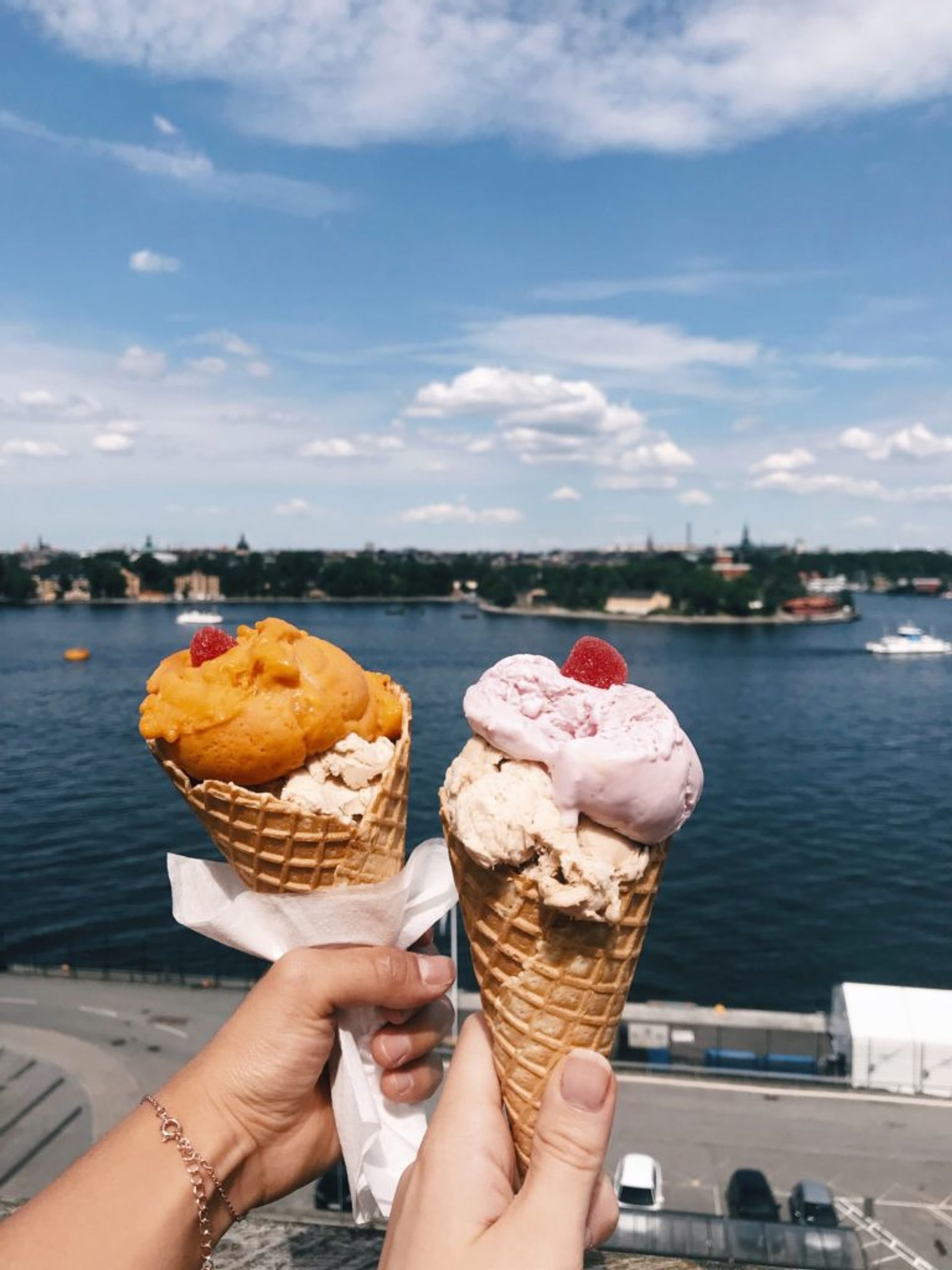 Two hands holding two cones of ice cream.