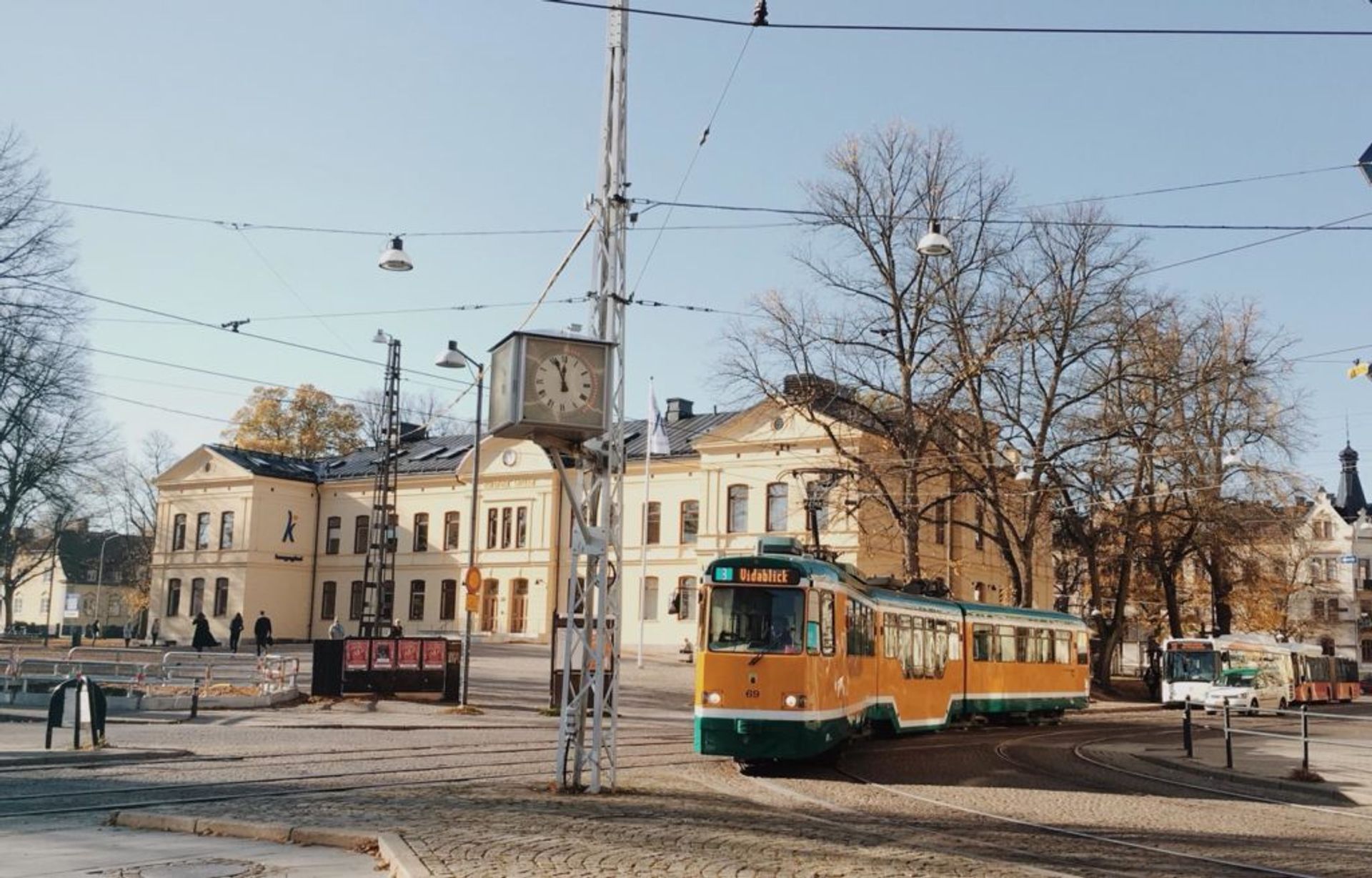 Yellow and green tram passing by a cream coloured building.