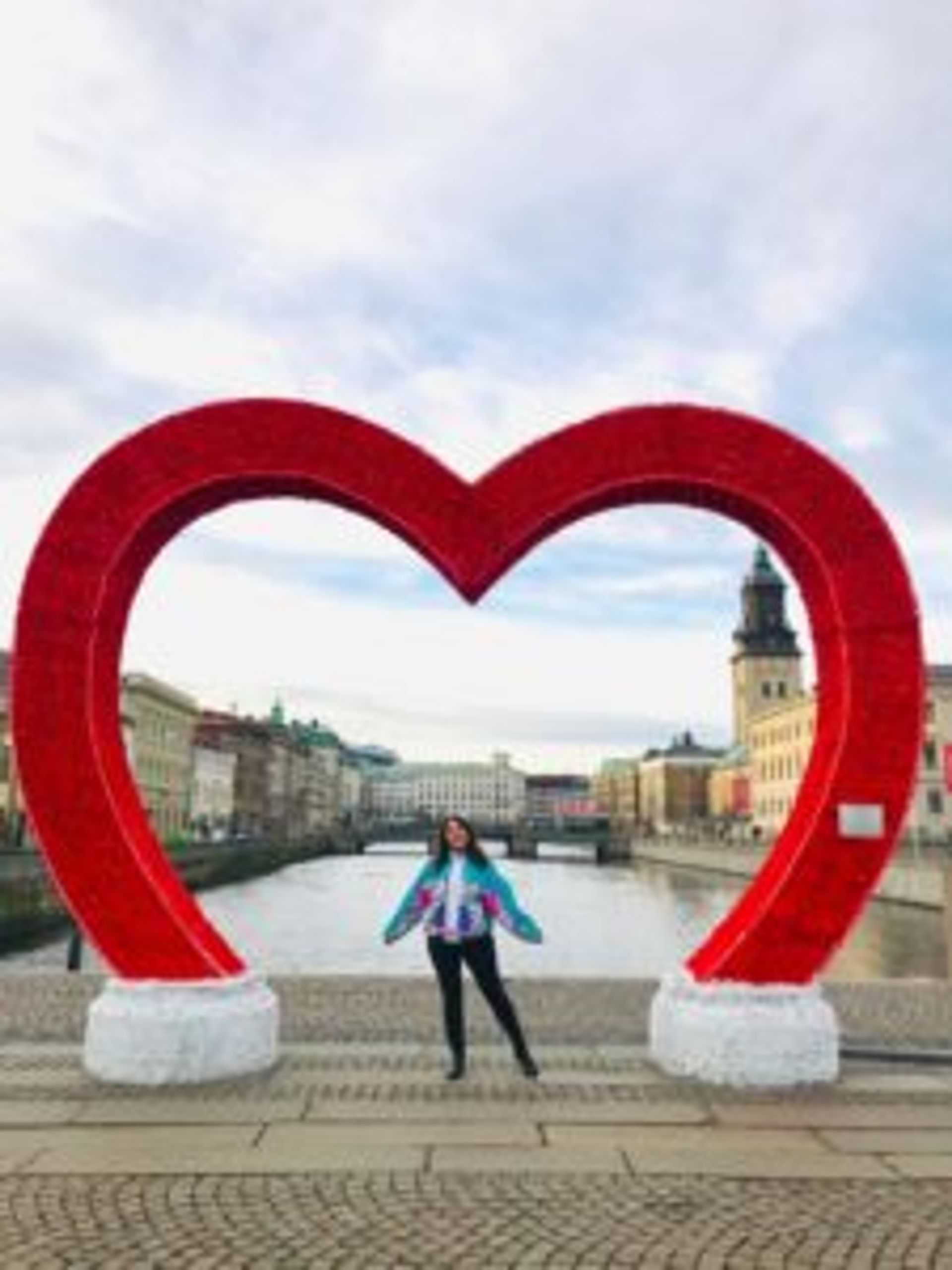 Hazal standing under a large, red heart Christmas decoration.