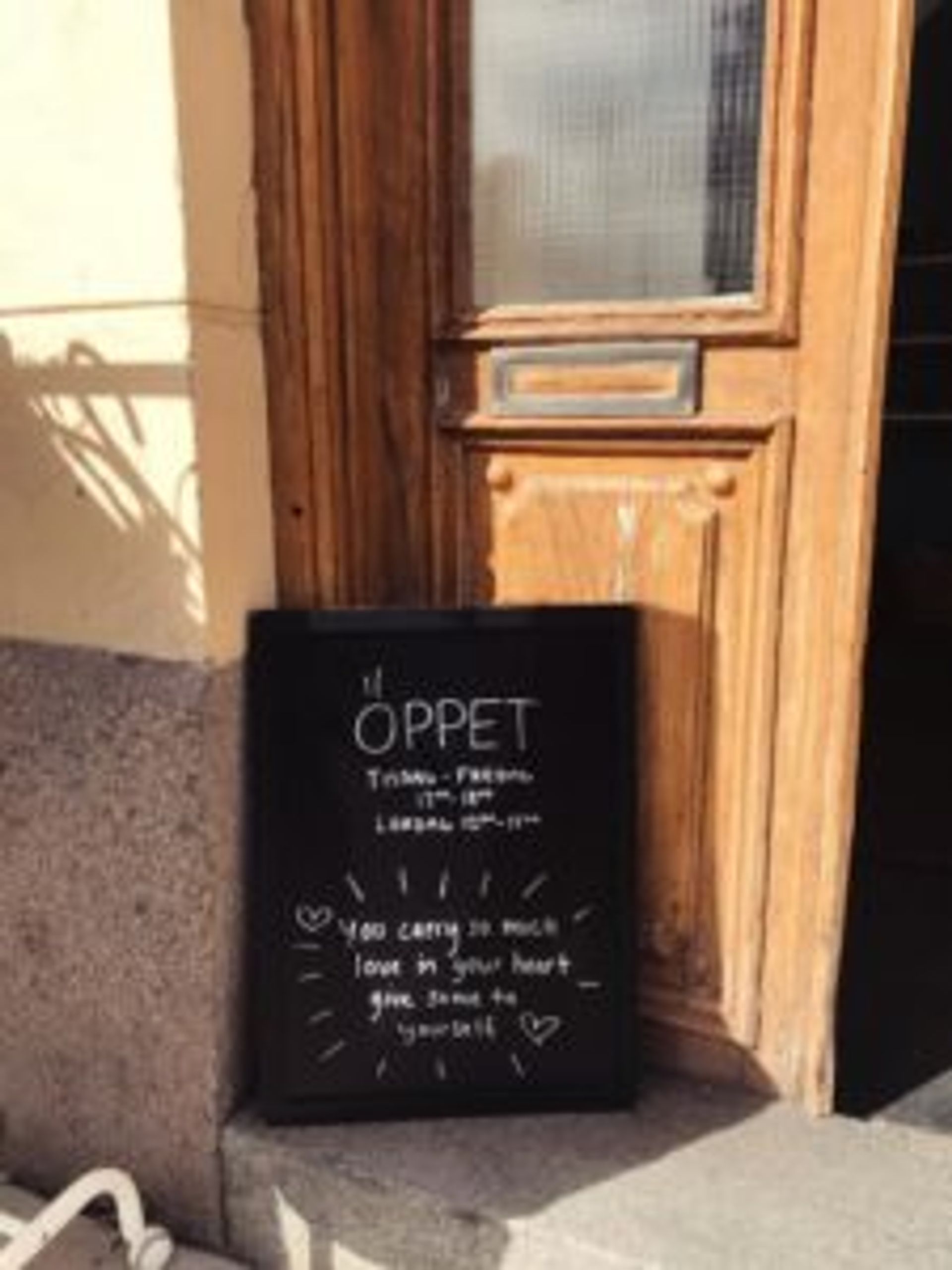 A wooden door with a sign outside. The sign says 'Öppet' which means Open in Swedish. 