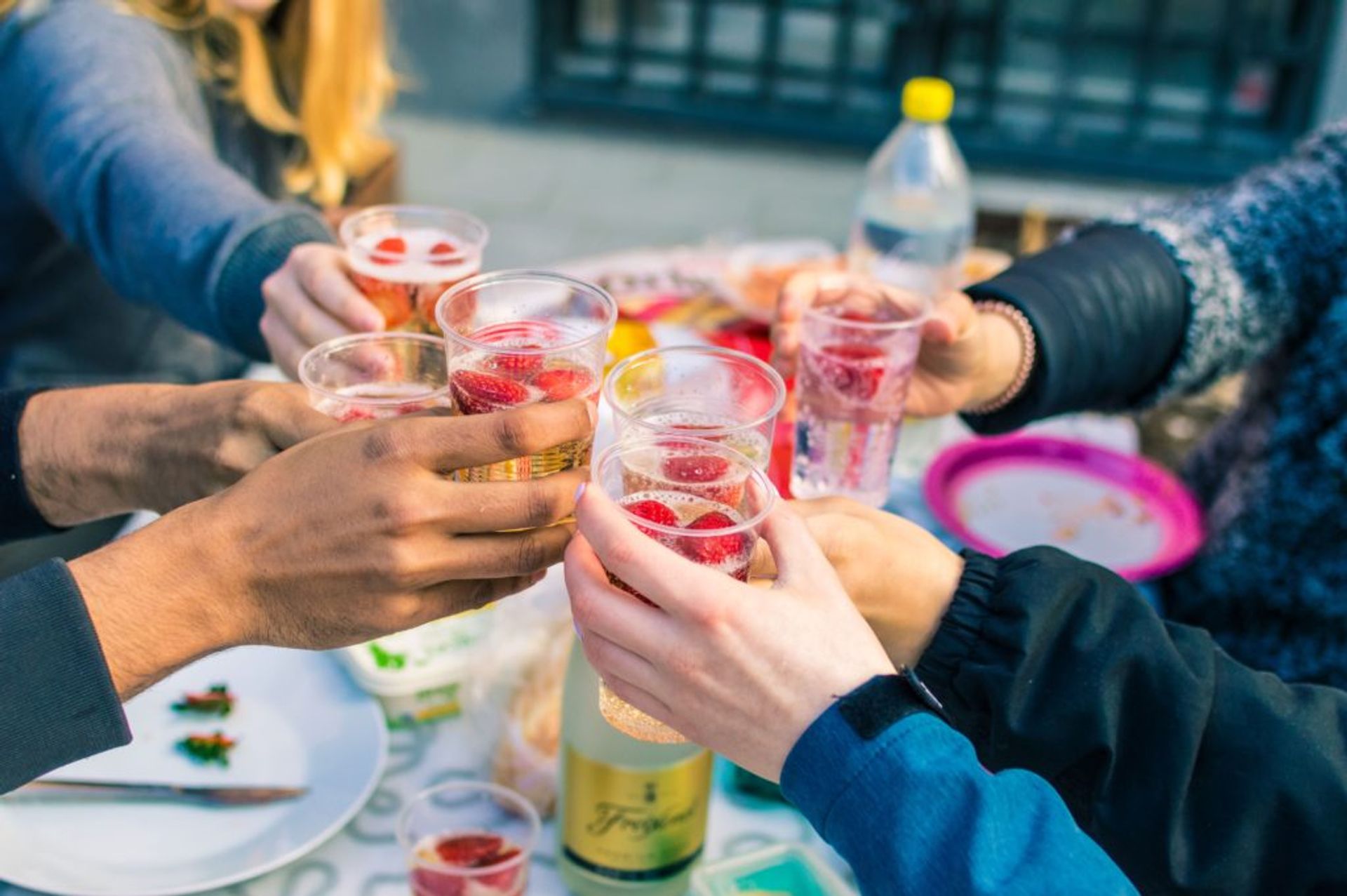 People toasting each other and clinking plastic cups together.