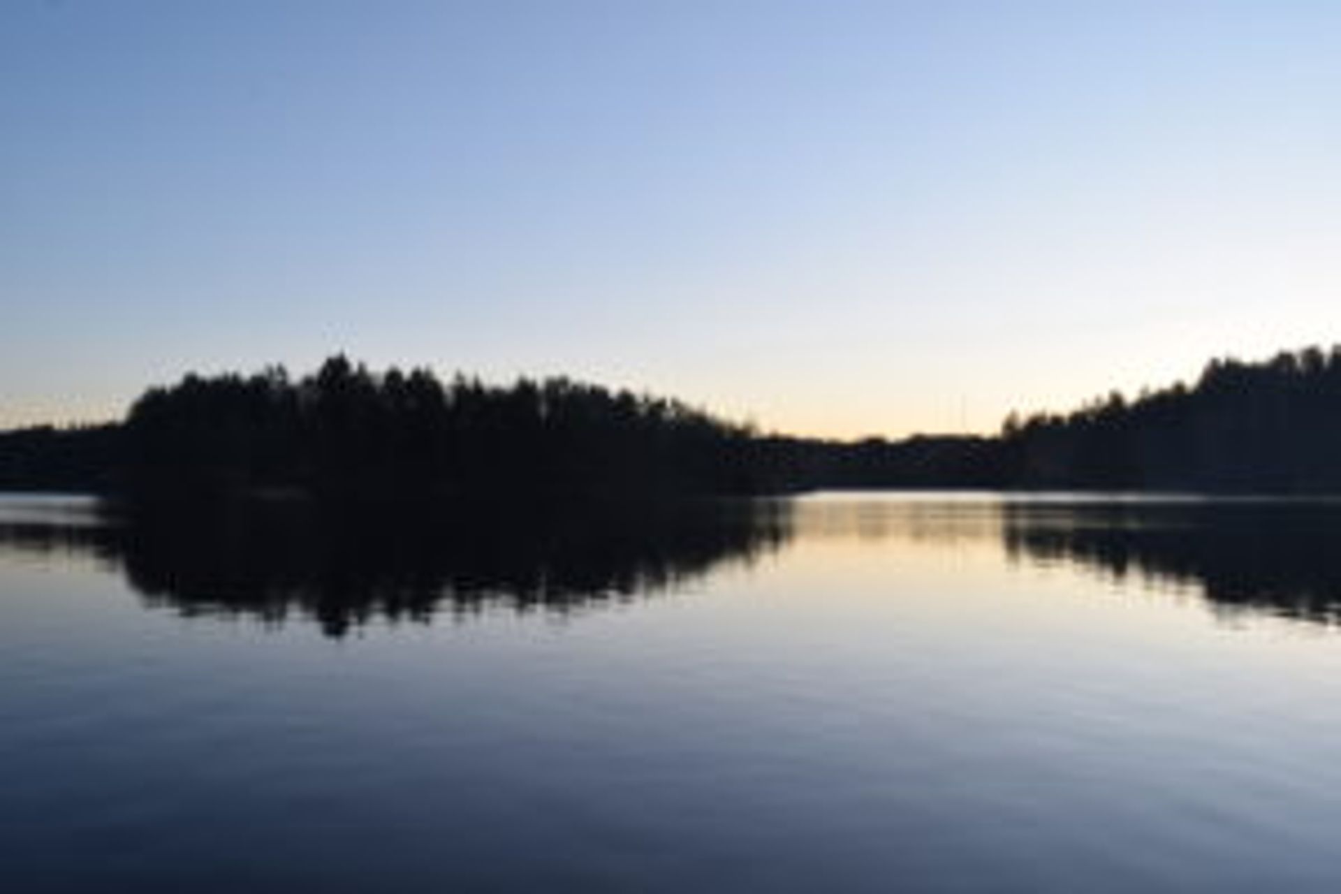 The lake, Delsjön. The water is completely still and the forrest is reflected in the water.