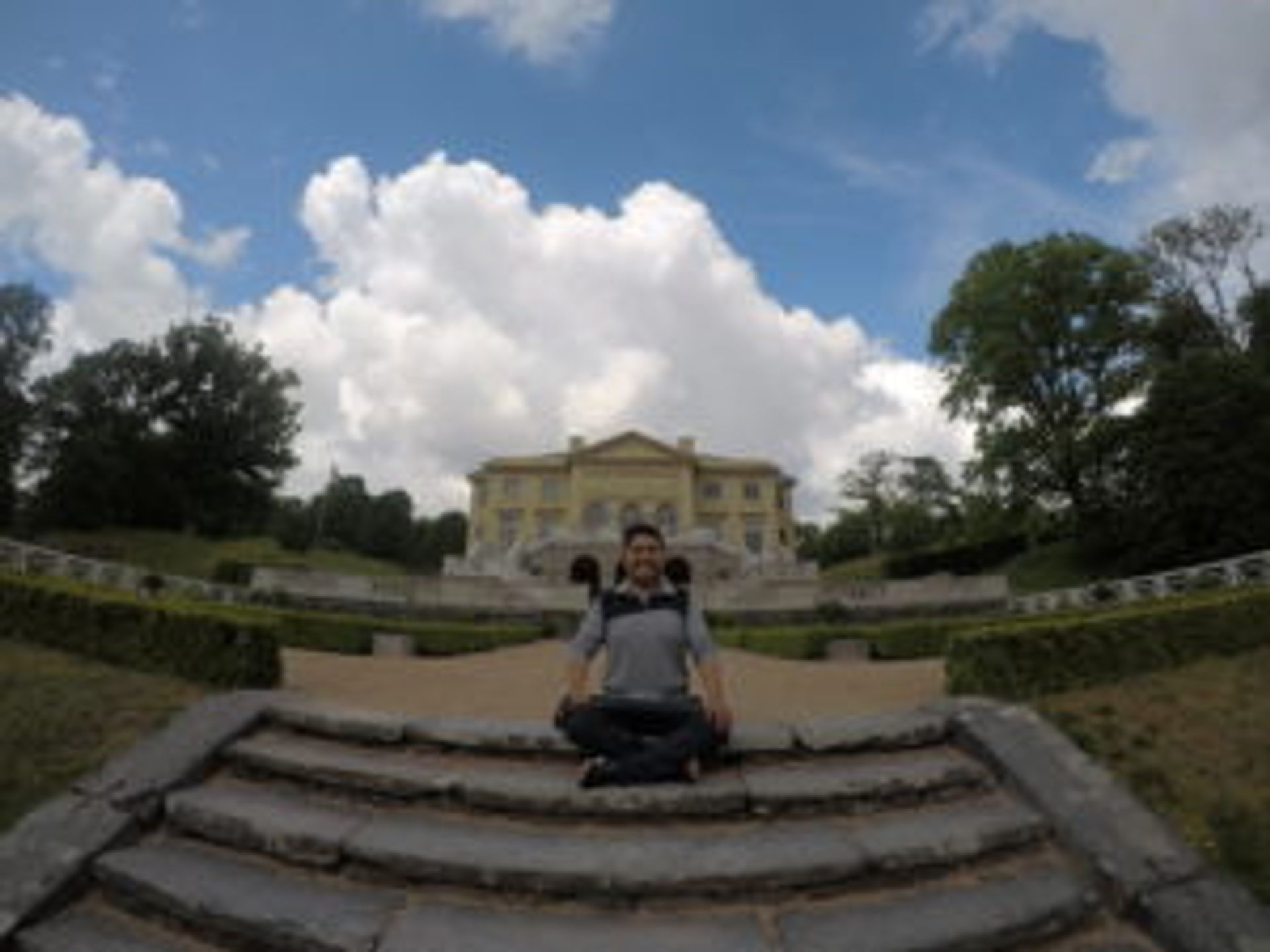 Camilo sits on the steps in the Gunnebo House gardens. The house is pictured in the background.