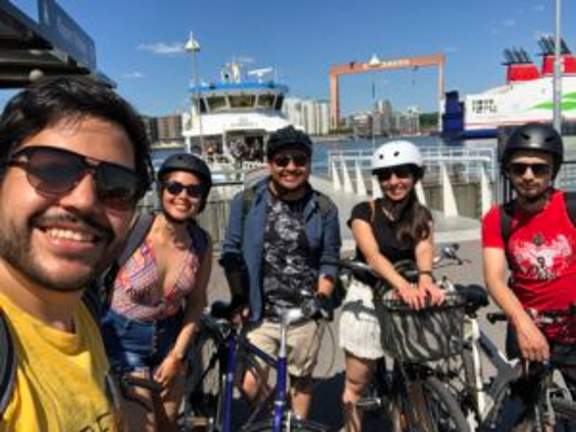 Camilo and three friends stand in front of a ferry with their bicycles.