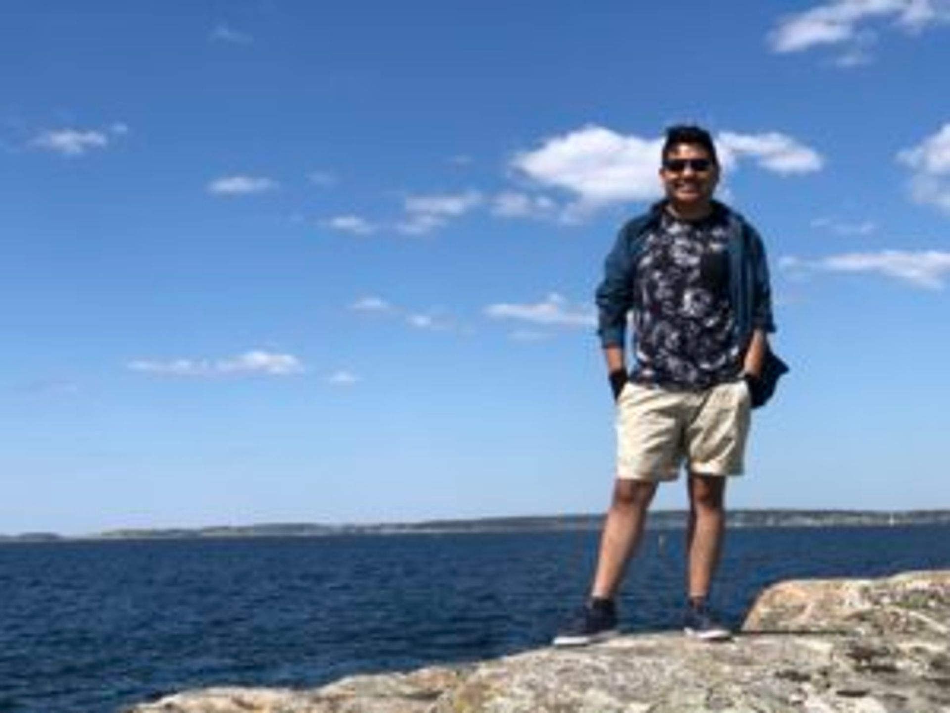 Camilo stands on a rock in front of the water.