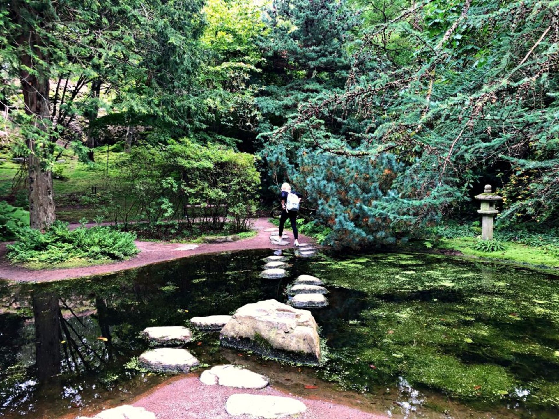 Sara crossing over a small river using  using stones that stick out of the water.