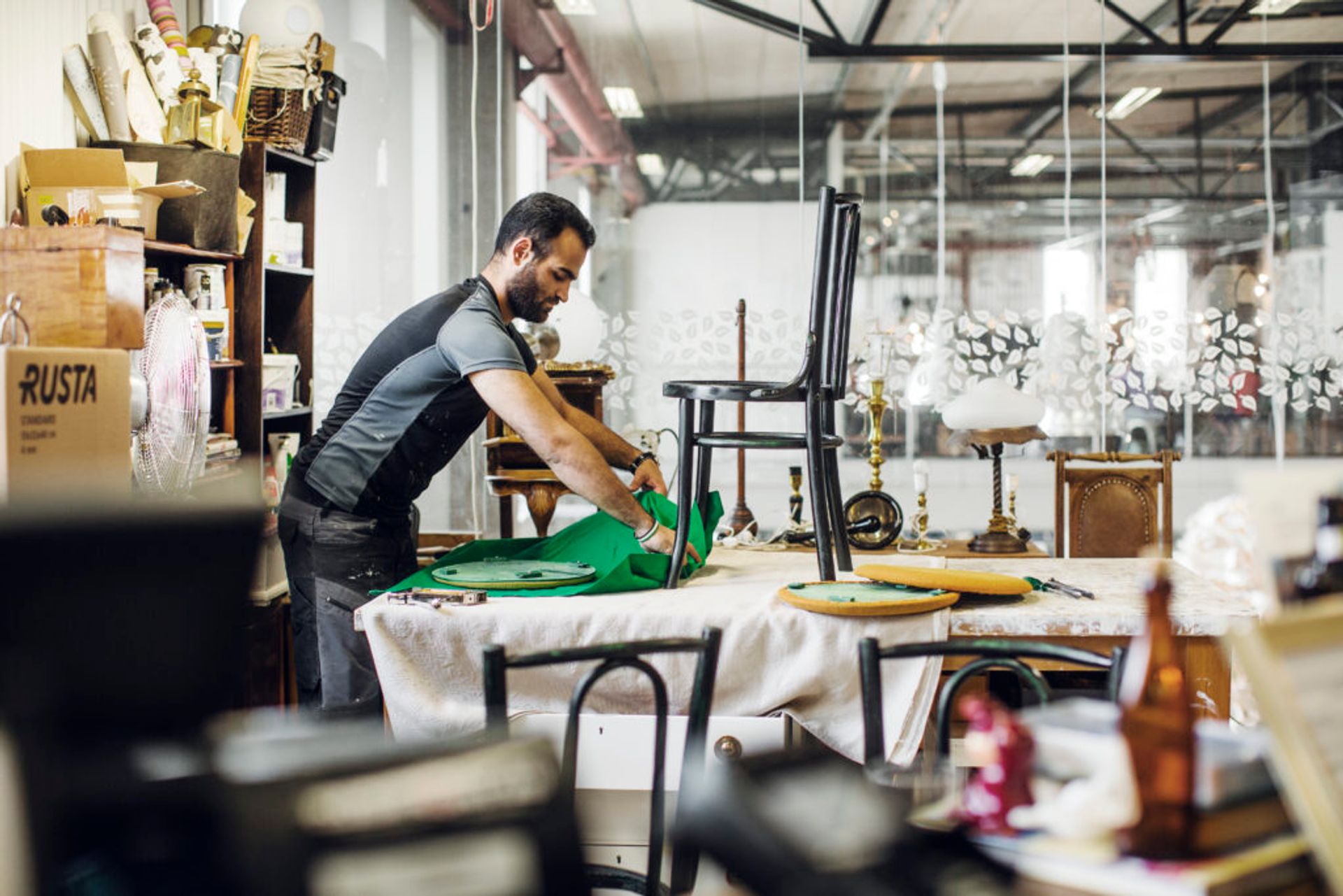 Man reupholstering a black, wooden chair in Returna.