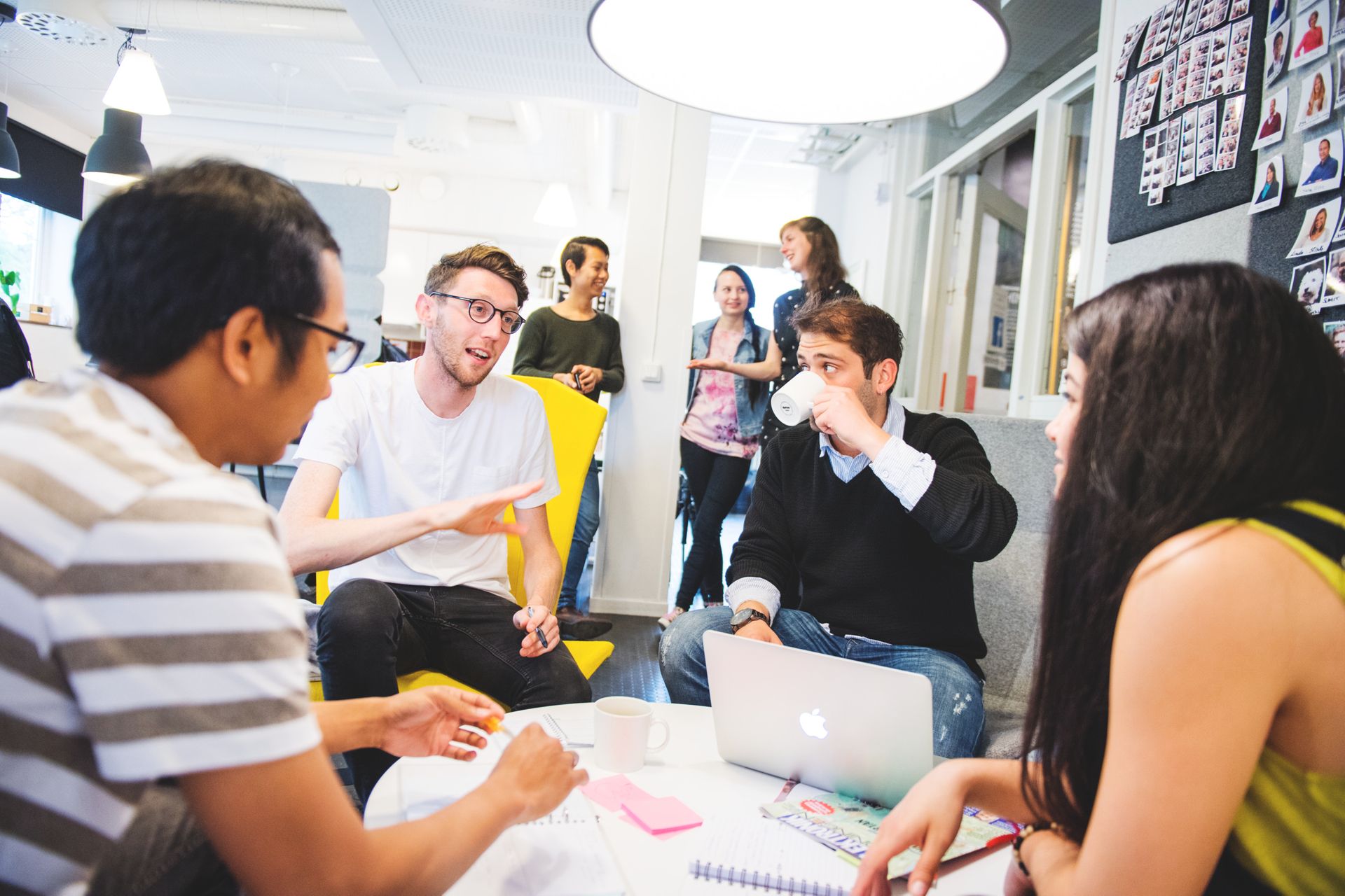 Group of students sitting at a table drinking coffee and working on a group project together.