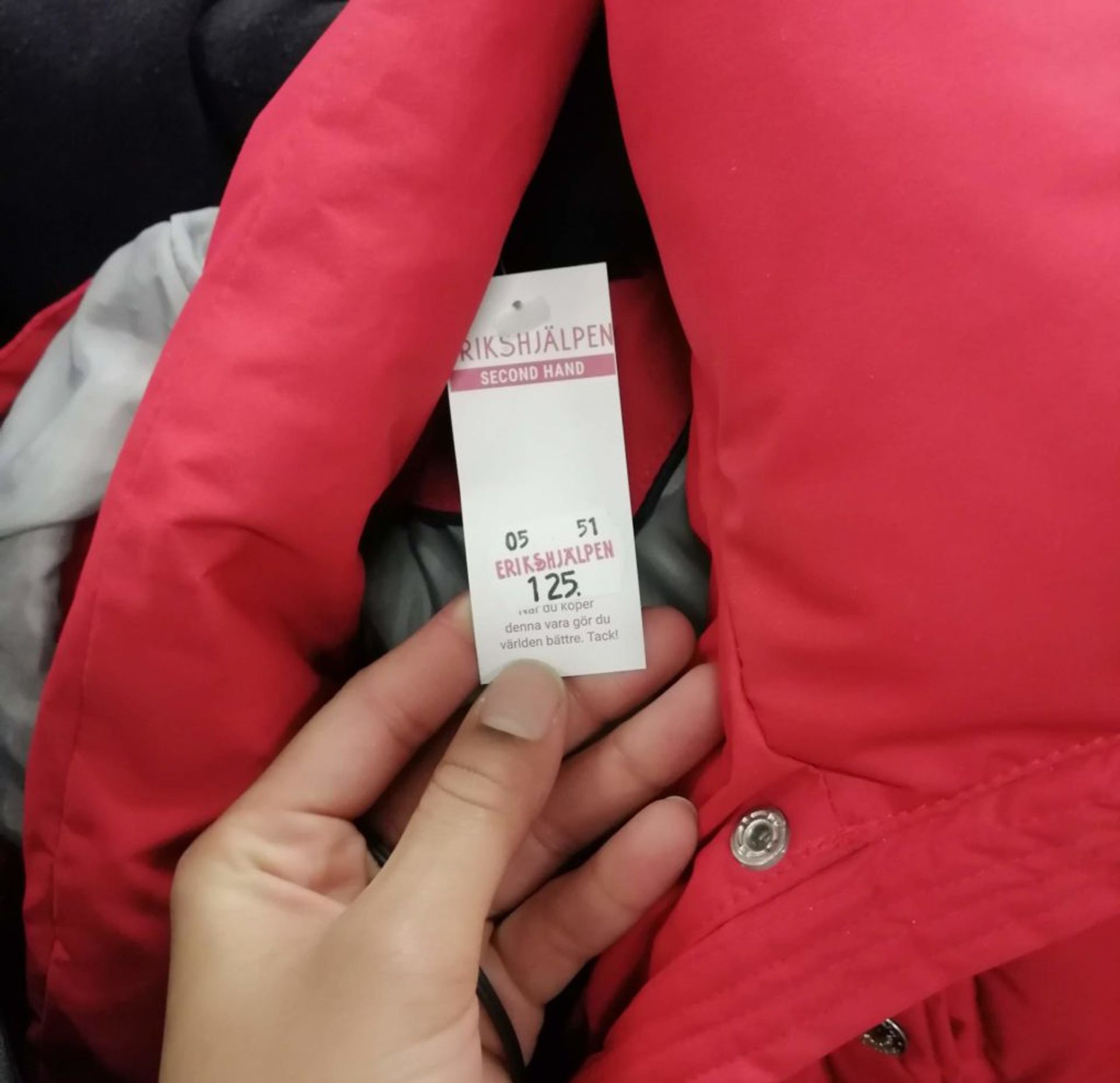 A red winter coat with a Erikshjälpen price tag. The price tag show that it's  SEK 125.