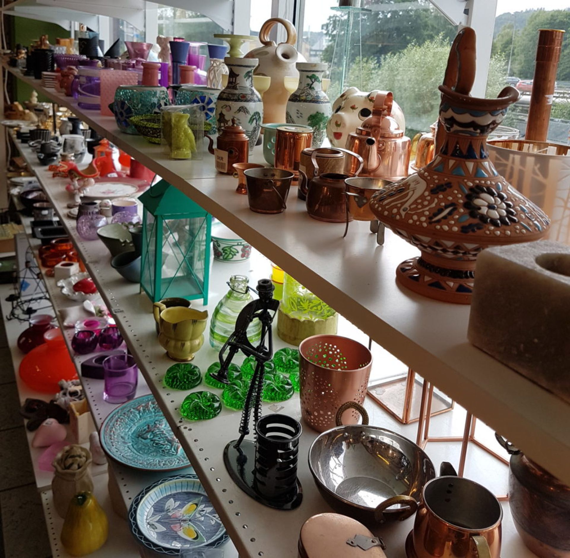 Decorations, trinkets, plates and glasses on a shelf.