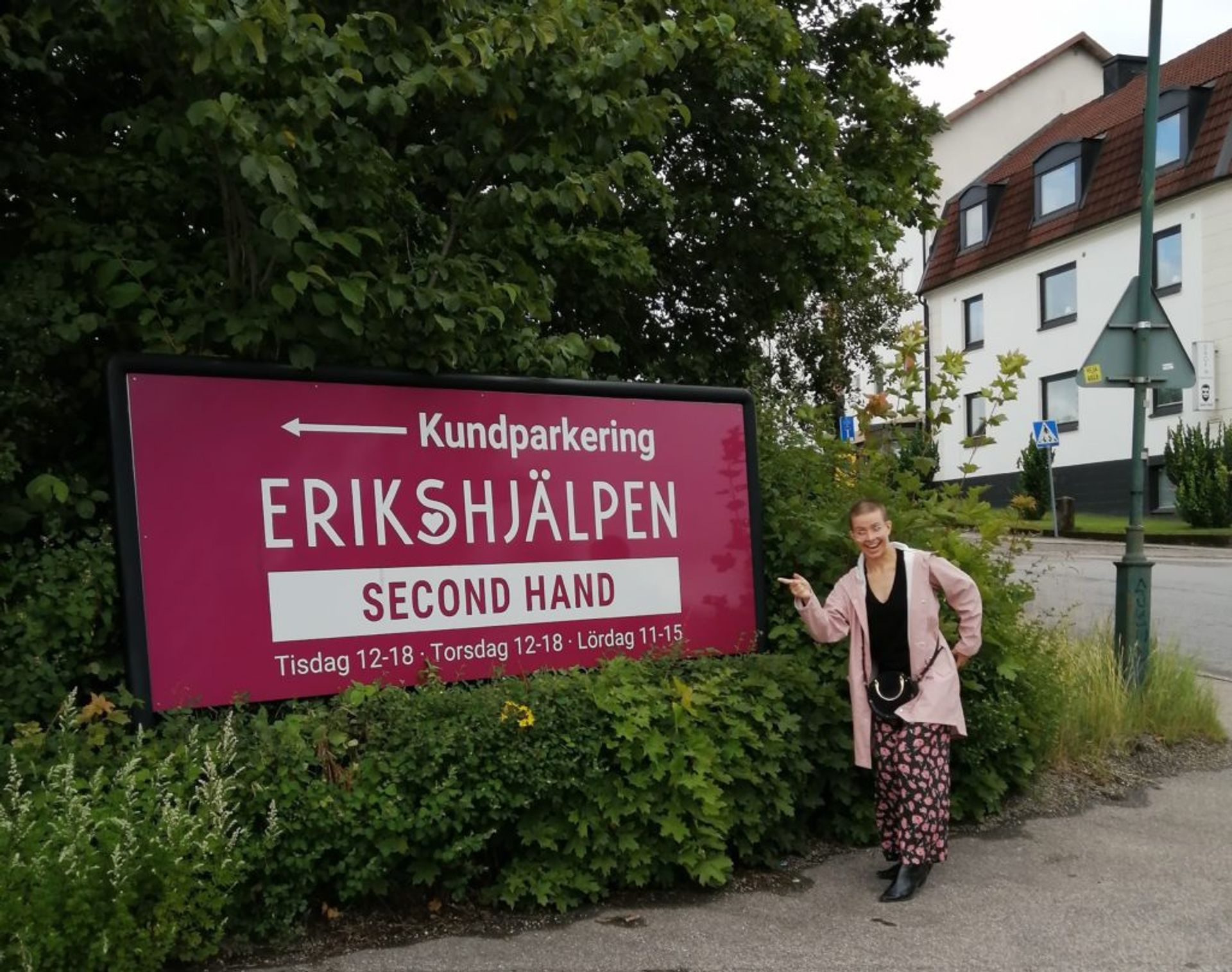 Lusanda's friend Vera standing by the sign pointing to the Erikshjälpen second hand store.