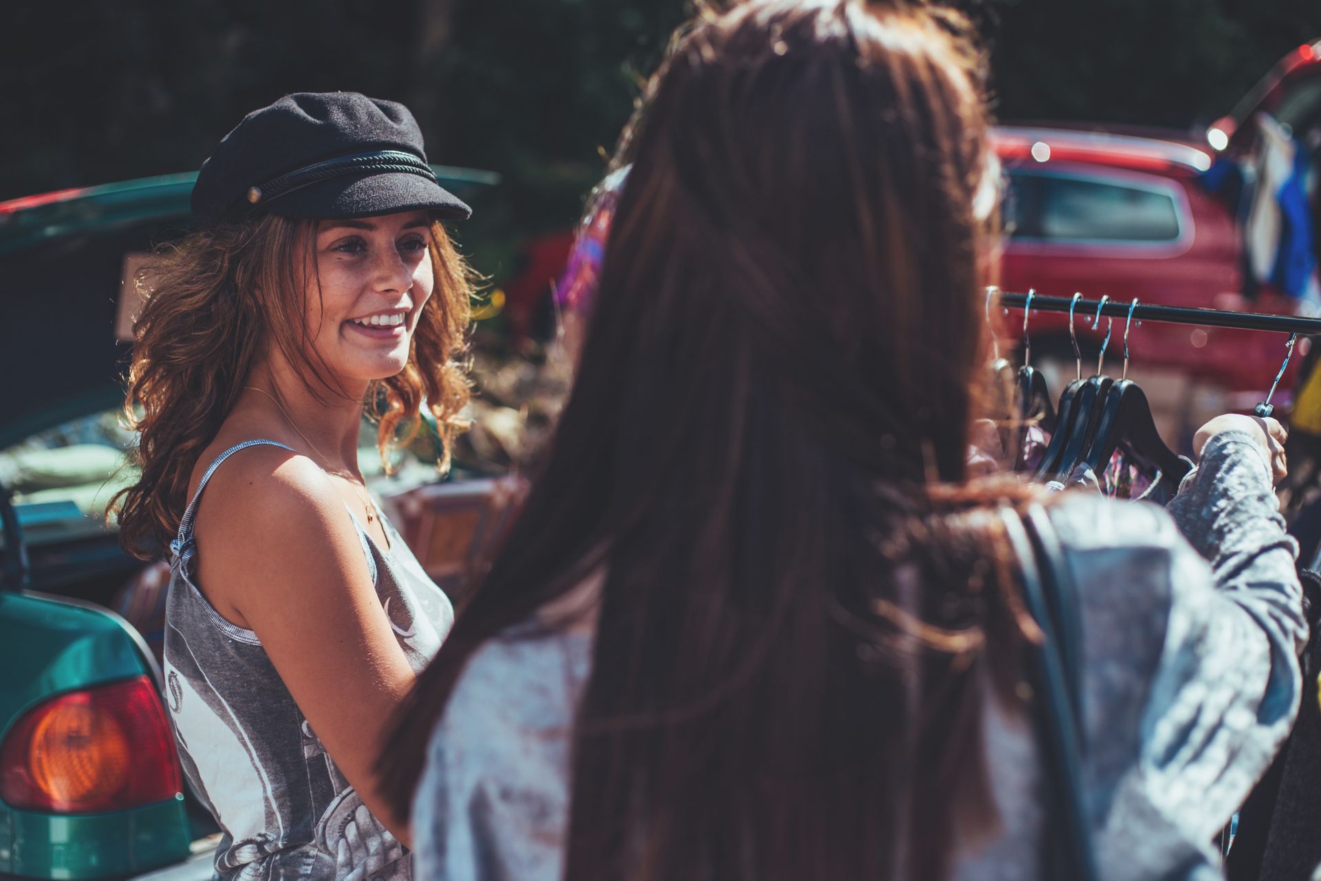 Two women browsing through racks at a flea market.