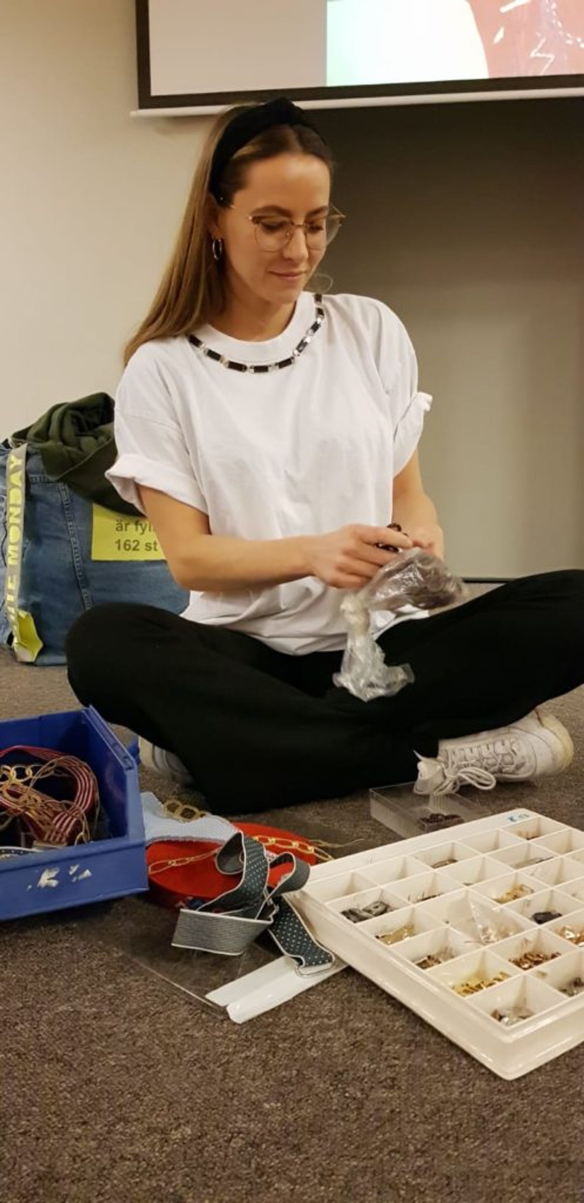 A student sitting on the floor mending clothes at the 2019 Hållbar student workshop.
