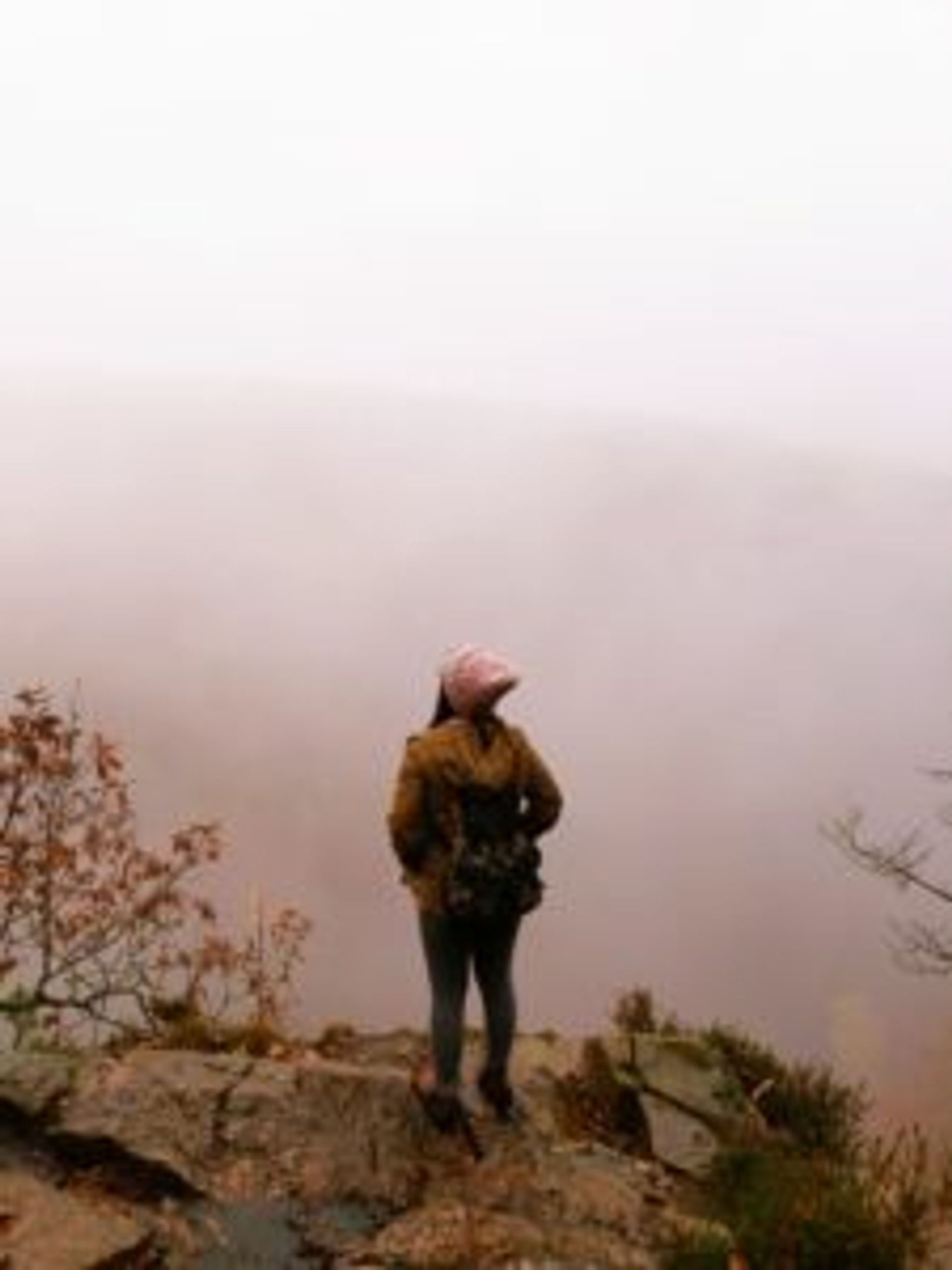 Nguyên standing on a cliff looking out over a misty valley.