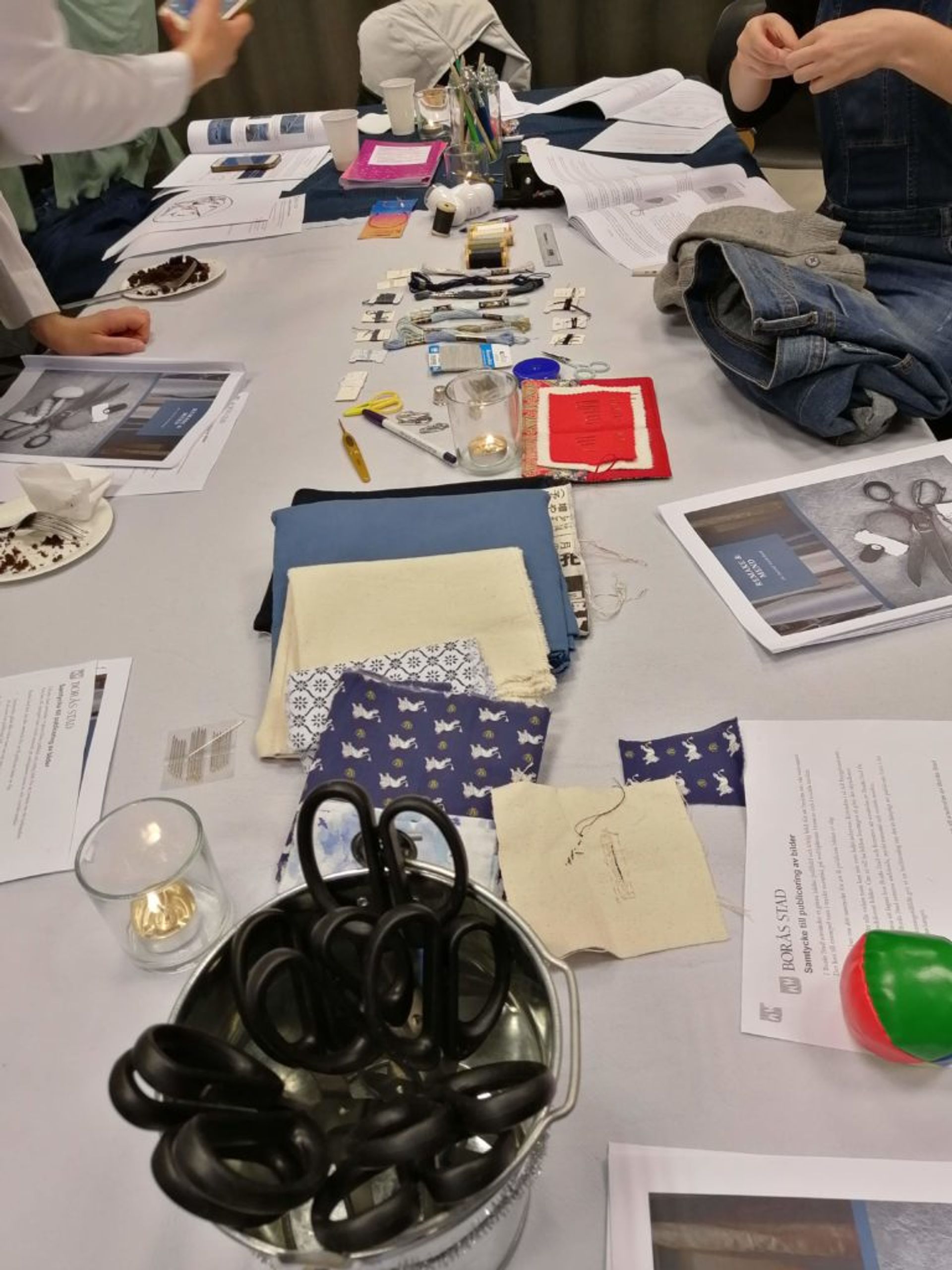 Scissors, fabric, pins, needles and threads on a table.