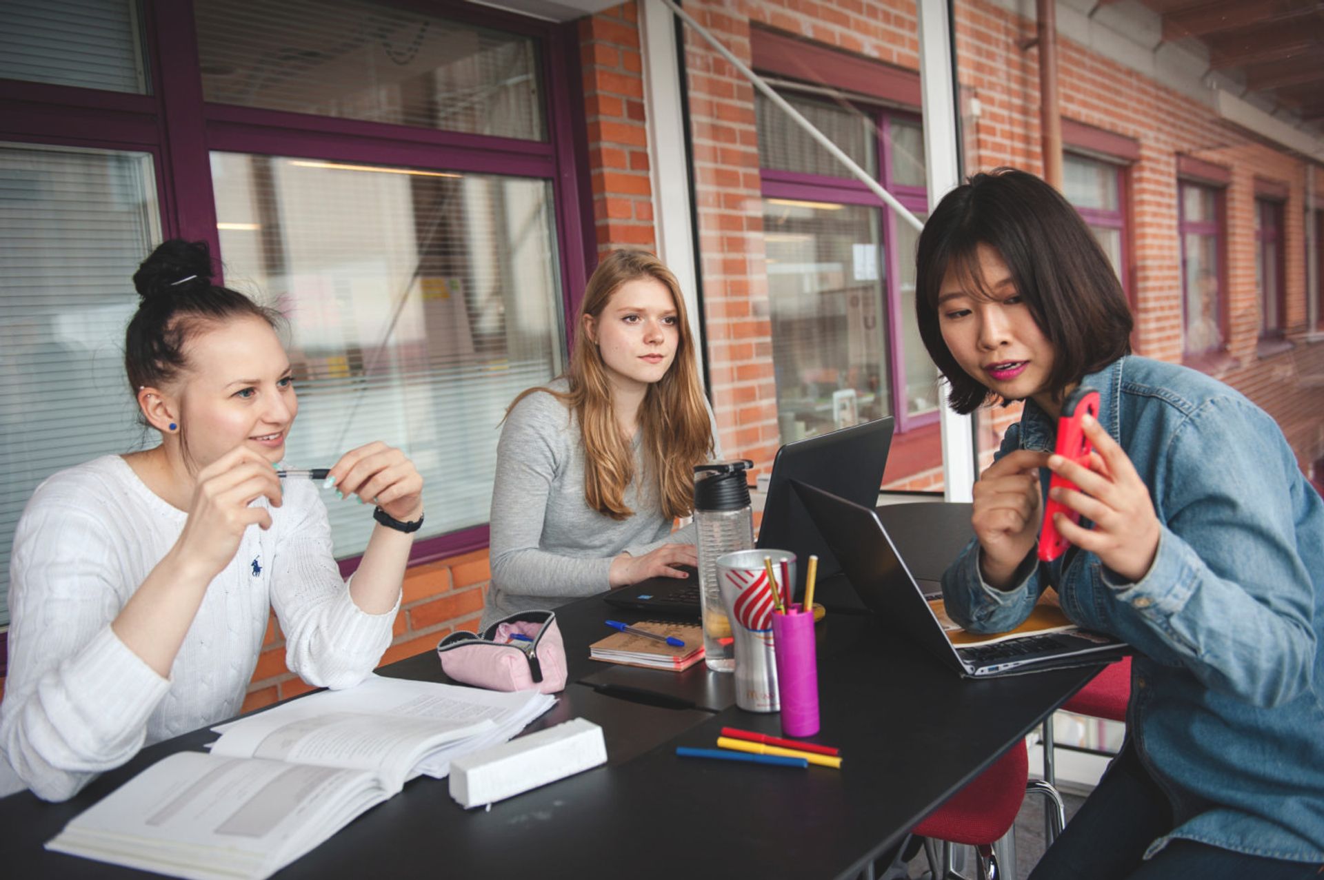 Three students sitting at a desk studying together.