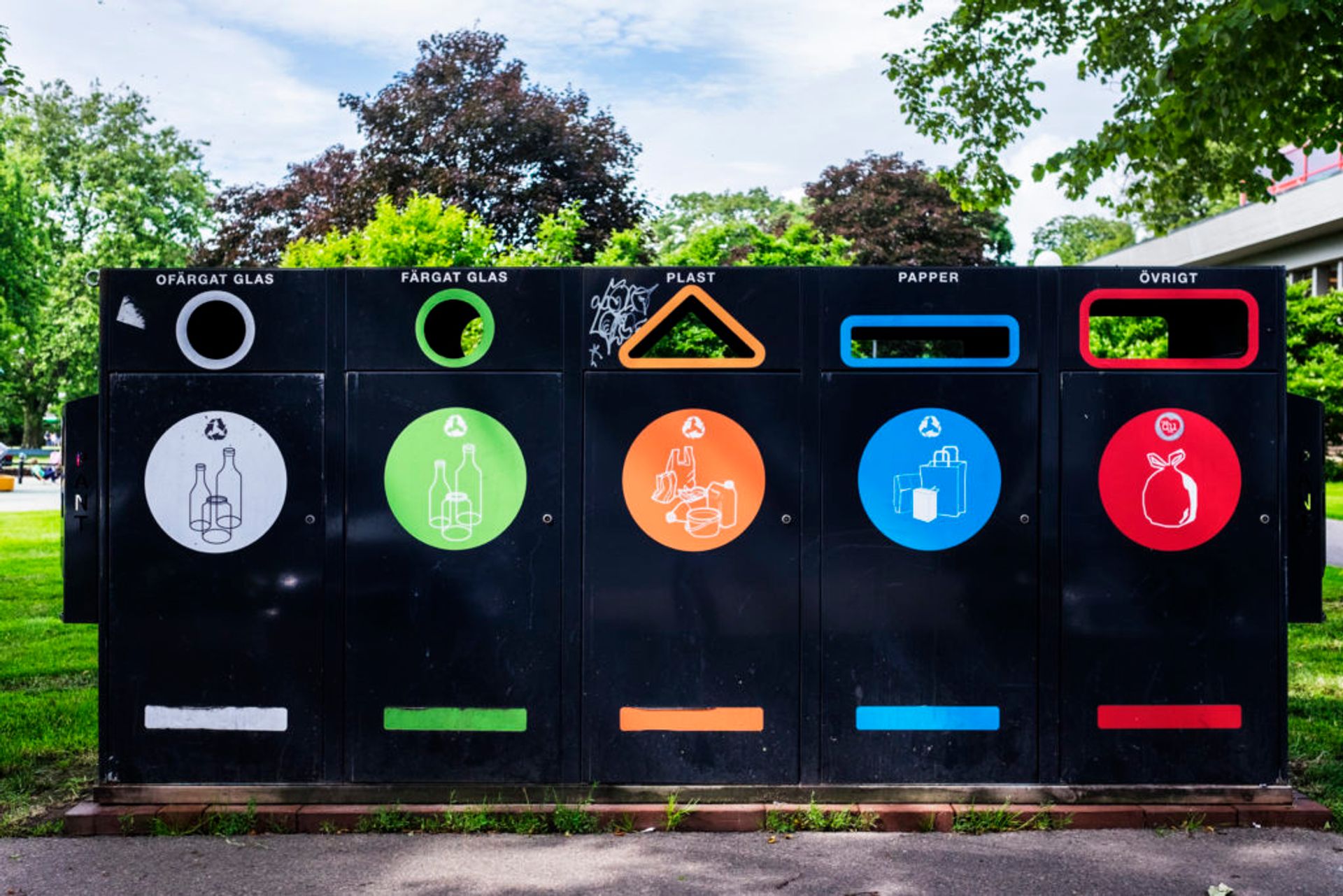 Recycling station for plastics, paper, coloured glass and clear glass outside a residential building. 