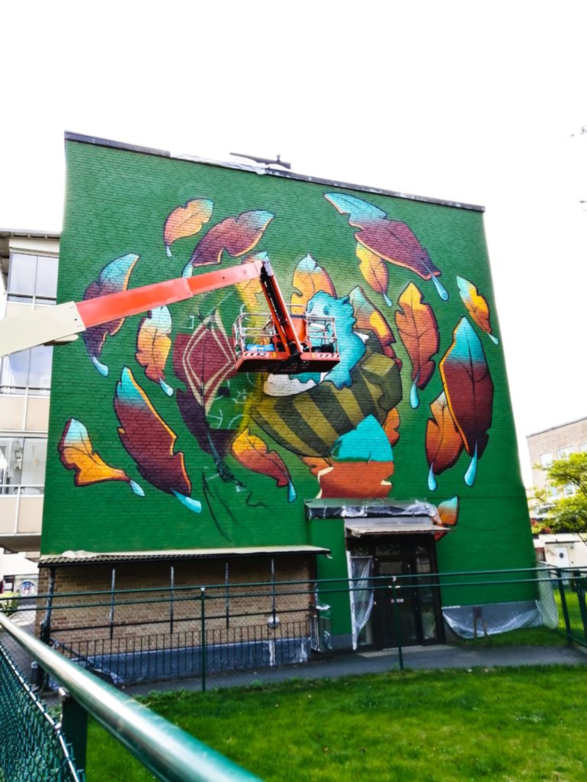 Colourful and animated mural of character riding a teacup surrounded by glowing leaves on the side of a building.