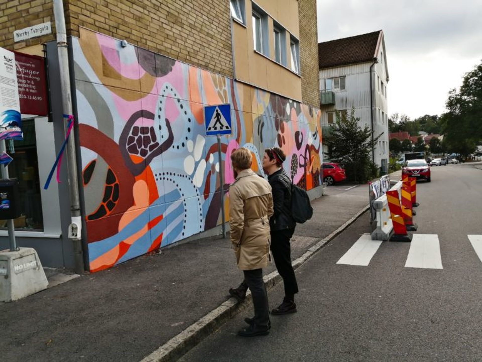 Two men standing and looking at a mural in Borås.