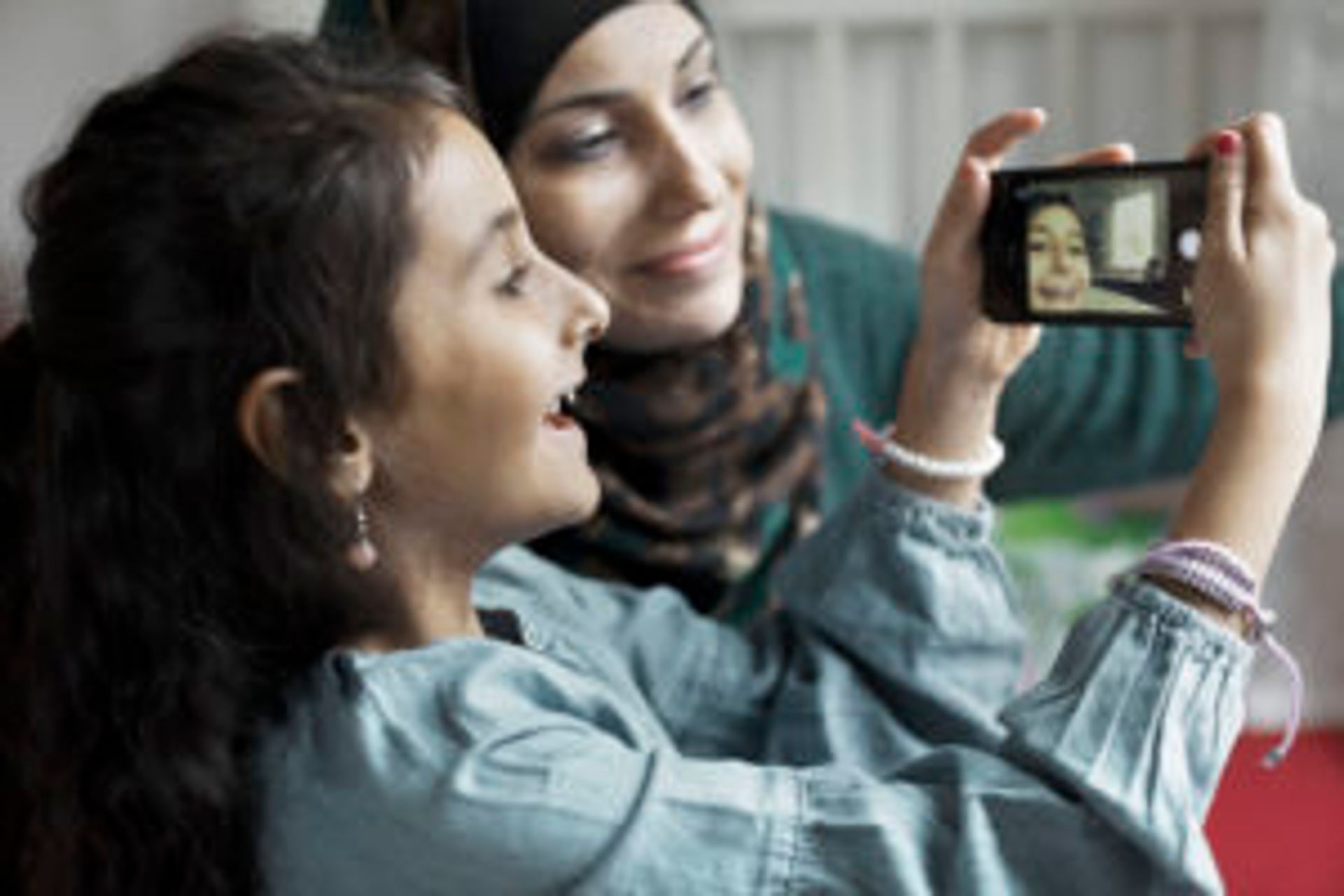 A smiling woman and child taking a selfie together. 