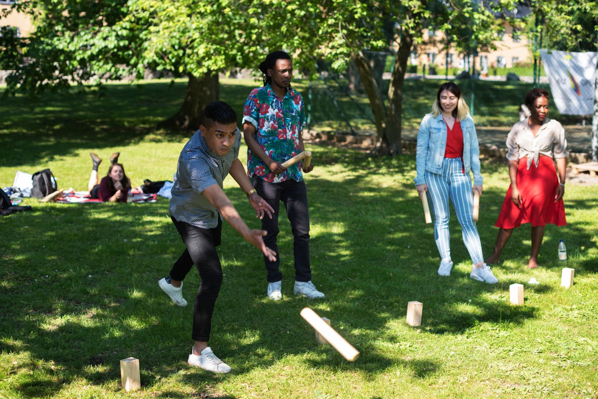 A group of international students playing the Swedish lawn game 'Kubb' in a partk.