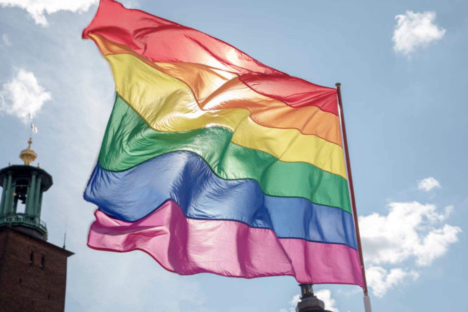Pride flag waves in front of blue sky in Stockholm