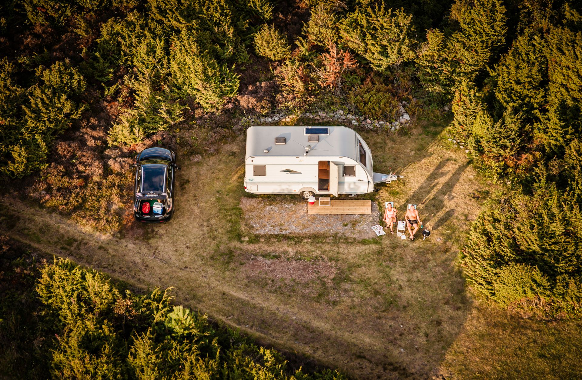 Picture Showing a caravan and two people tanning